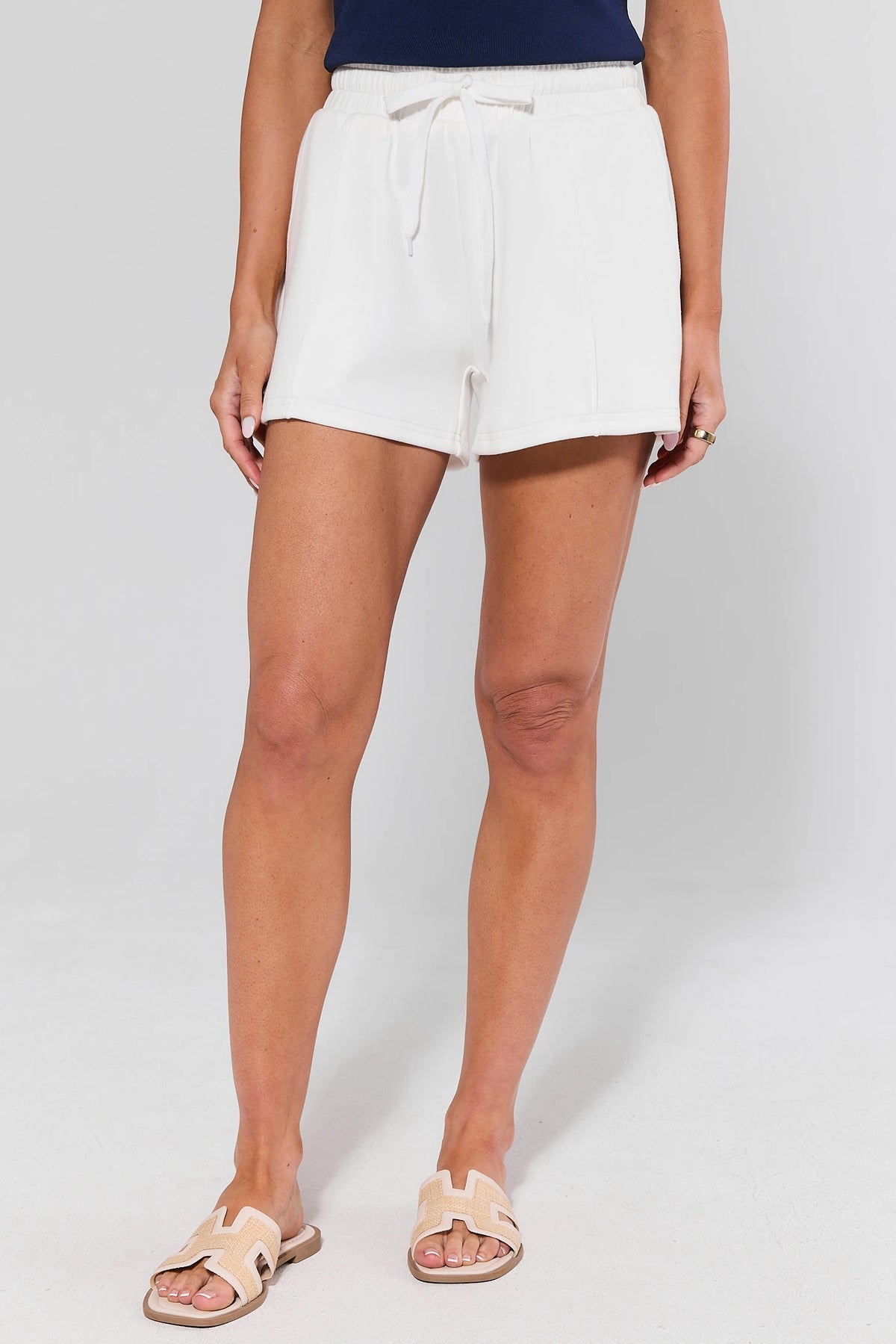 White Lexi Sweat Shorts styled with sandals - Full Length Front View | Avara