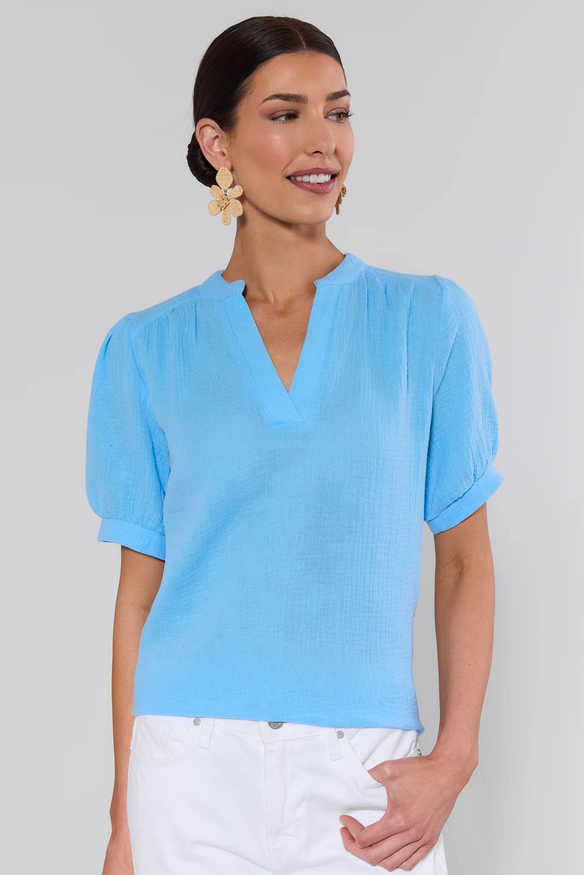 Woman wearing a light blue gauze blouse with puff sleeves and white pants, front view | Avara