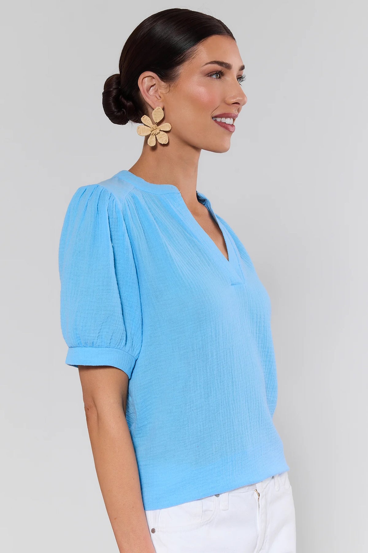 Side profile of woman in light blue gauze top showing puff sleeve and V-neckline detail | Avara