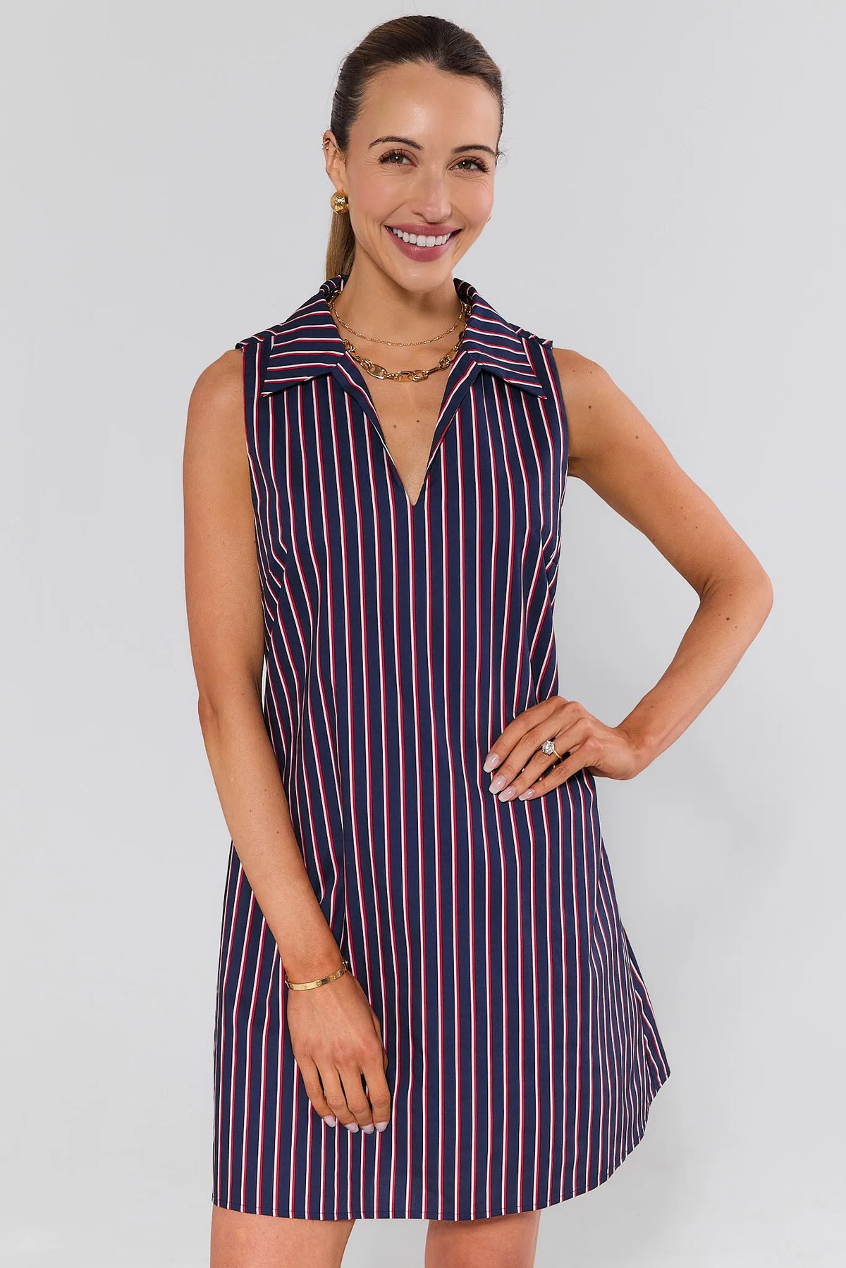 Woman wearing a sleeveless striped dress against a plain background