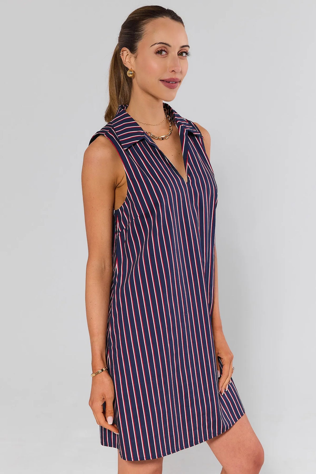 side shot Woman wearing a sleeveless striped dress against a plain background
