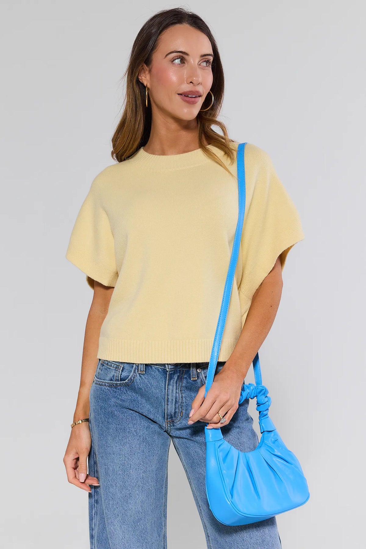 Woman wearing blue shoulder bag crossbody with yellow sweater and jeans - Styled Look | Avara