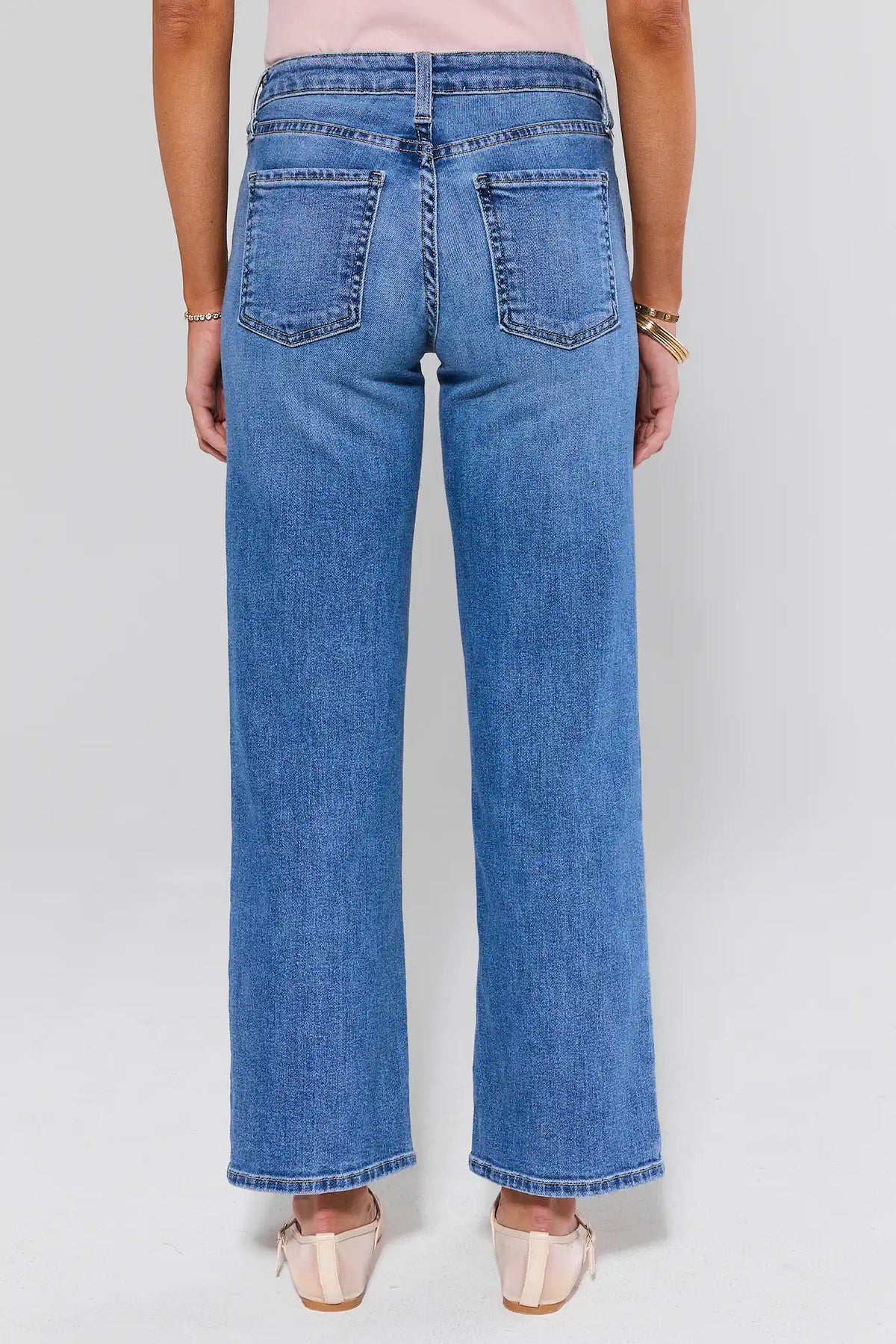 Person wearing blue jeans on a plain background