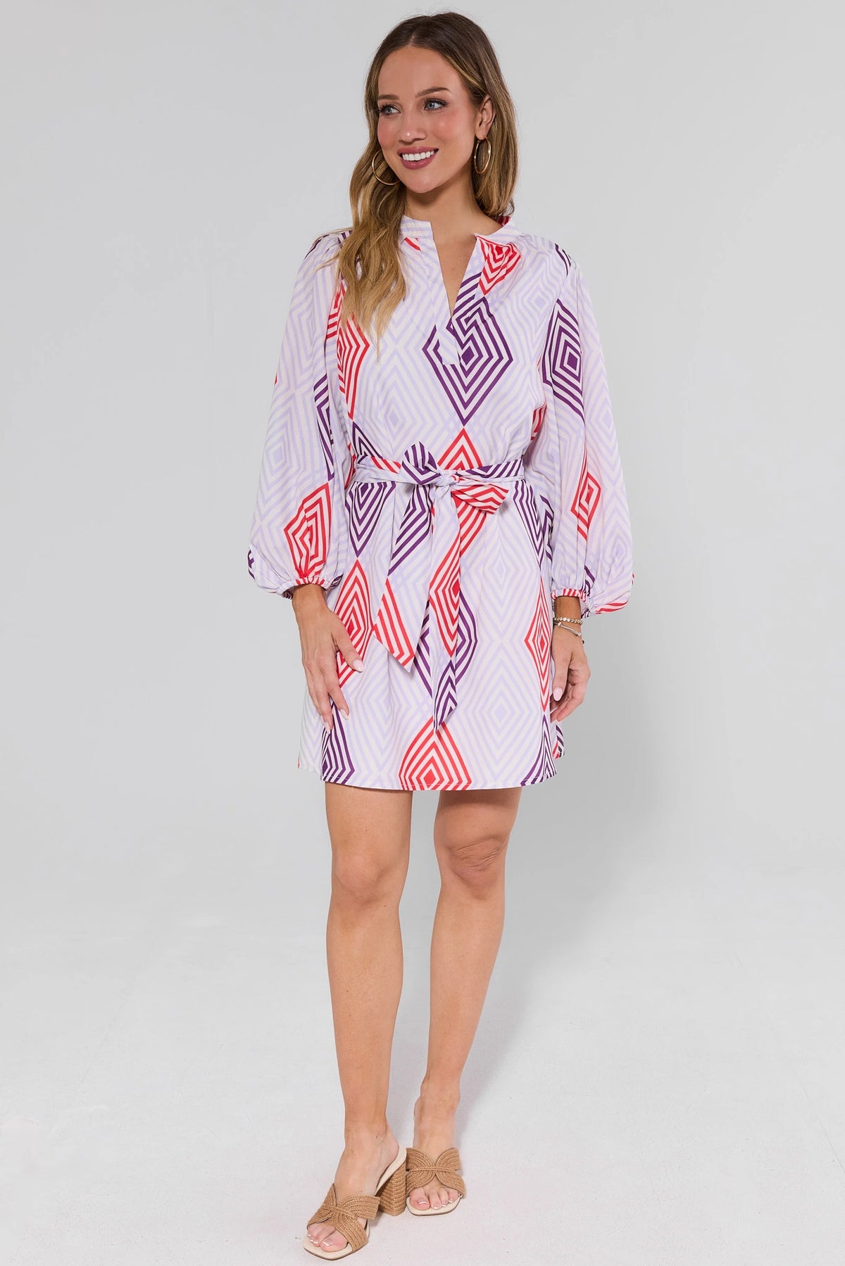 Woman wearing a patterned dress and heels on a plain background