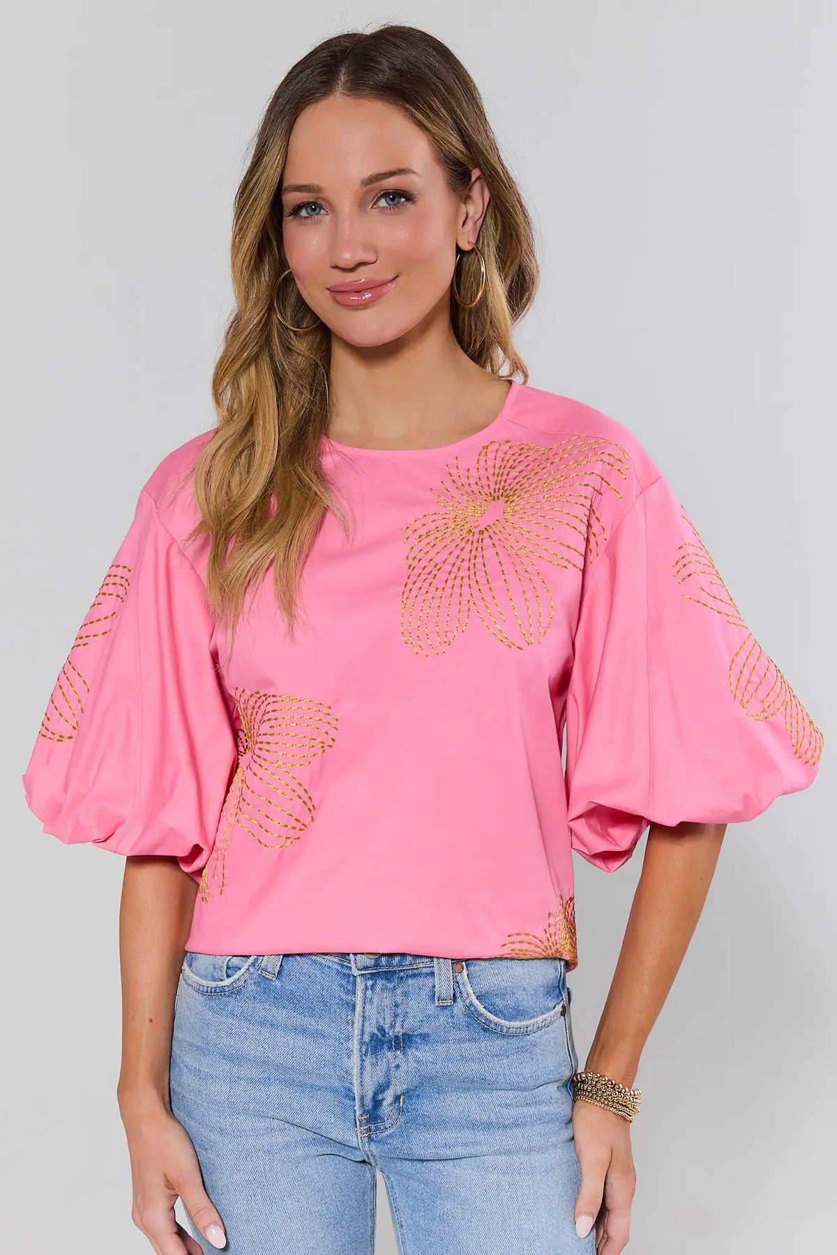 Pink Tara Embroidered Top with gold floral detail and puff sleeves, styled with blue jeans - Front View | Avara