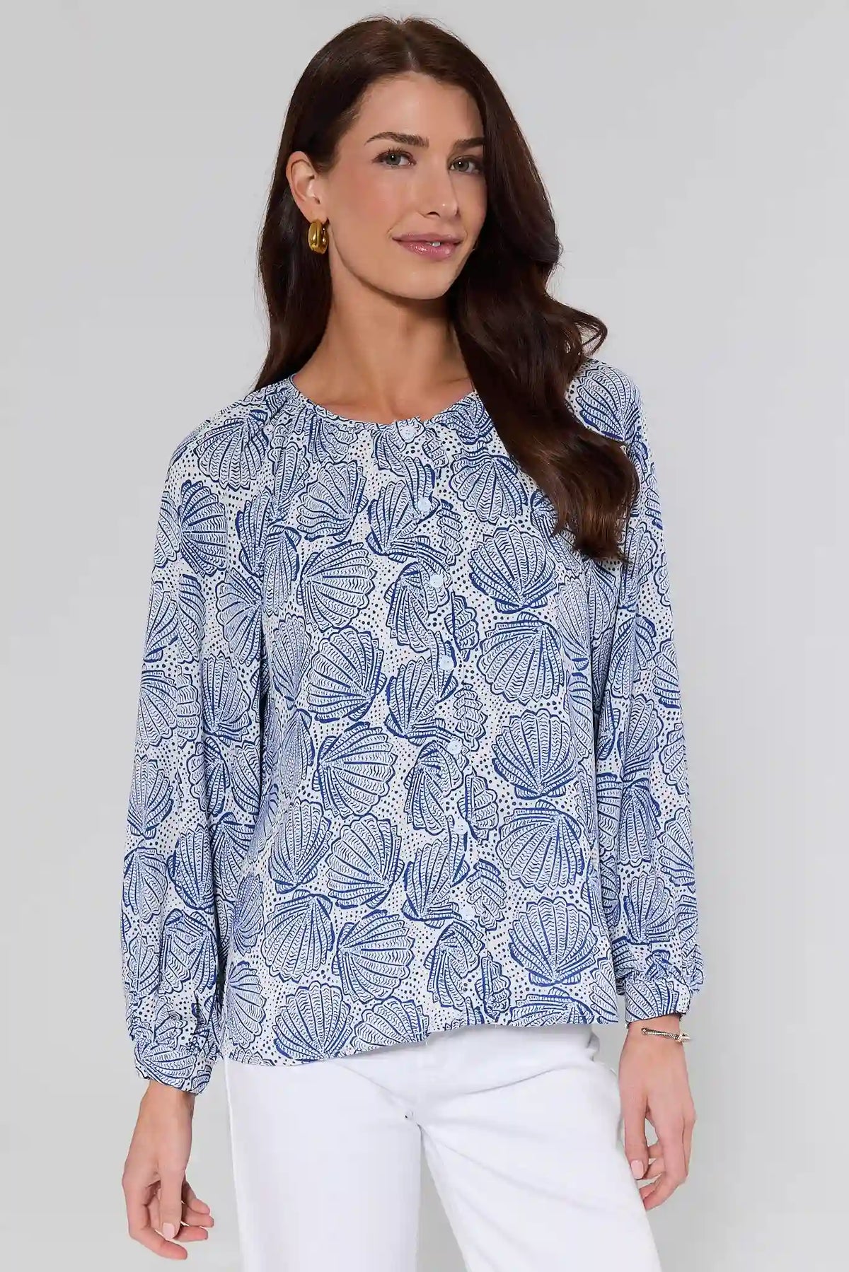 Woman wearing a blue shell print button-up top with long sleeves, front view, styled with white pants | Avara