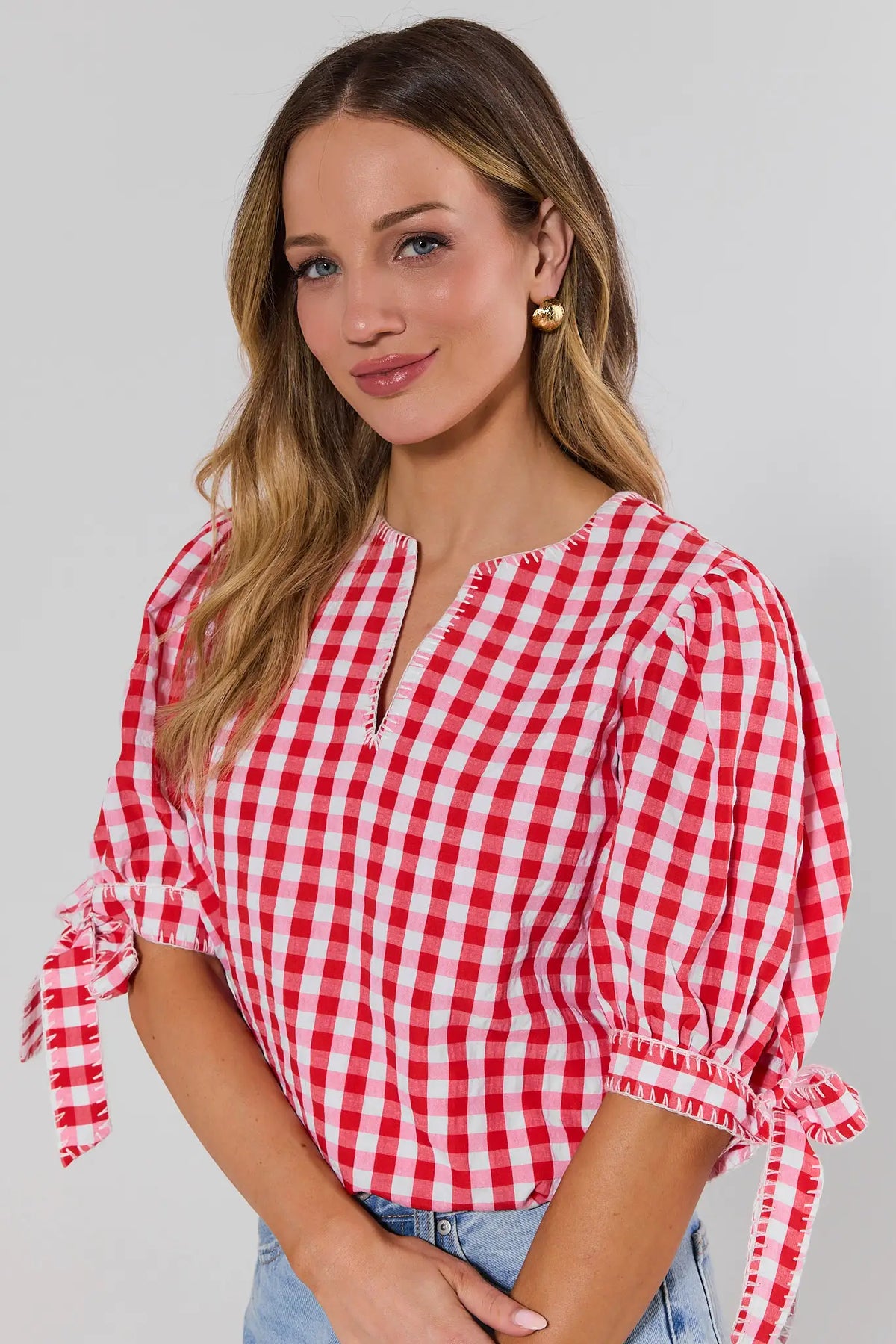 Close-up of red gingham puff sleeve top with tie detail sleeves and notched v-neckline | Avara