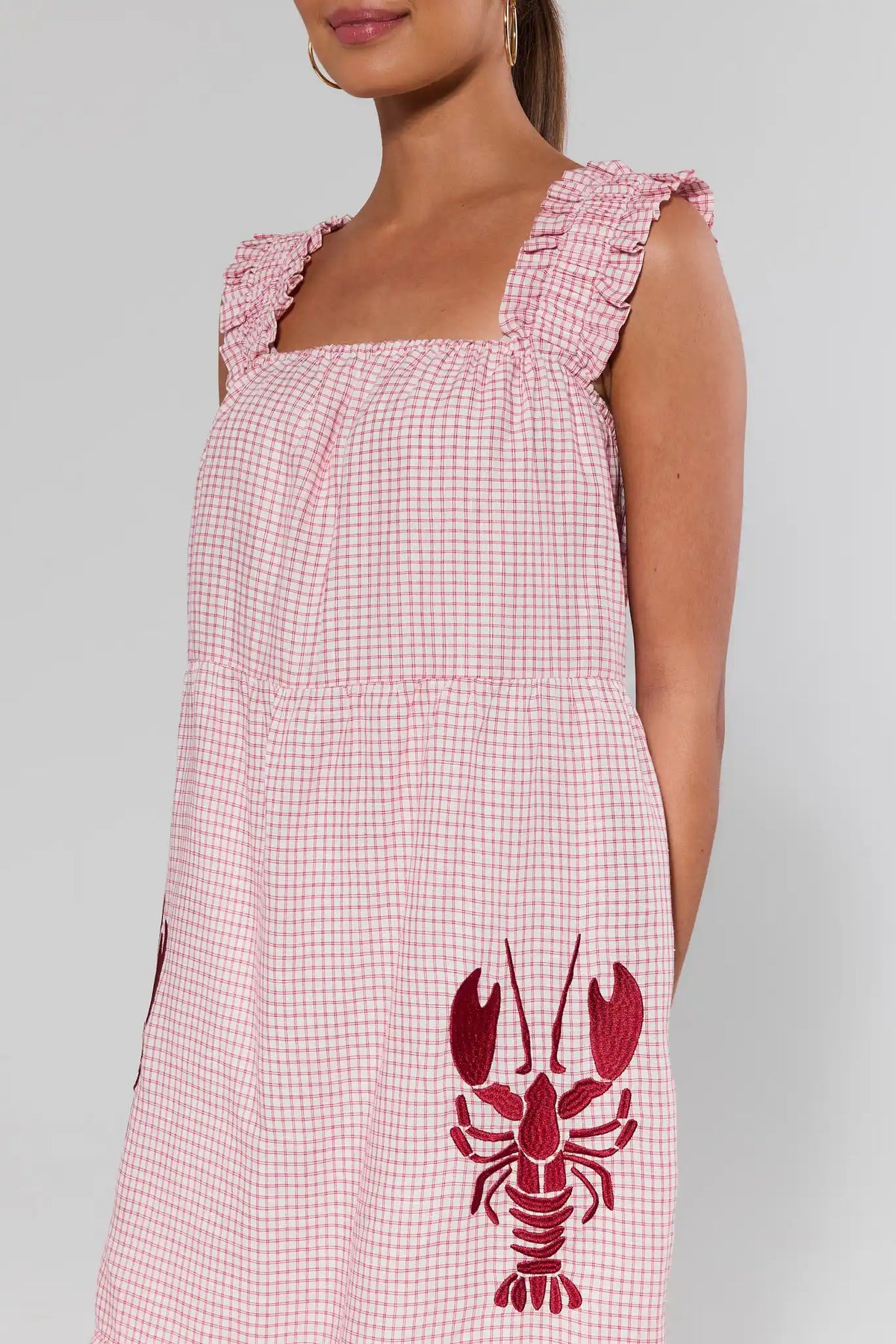 Close-up of red lobster embroidery and ruffle strap detail on red gingham midi dress, upper body view | Avara