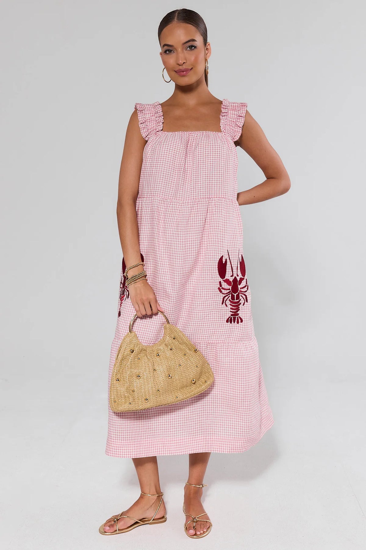 Red gingham lobster midi dress with ruffle straps, styled with gold sandals and woven bag, front view | Avara