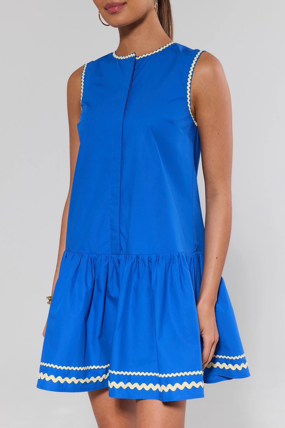 Blue drop waist mini dress with contrast ric-rac trim and ruffled hem, side close-up | Avara