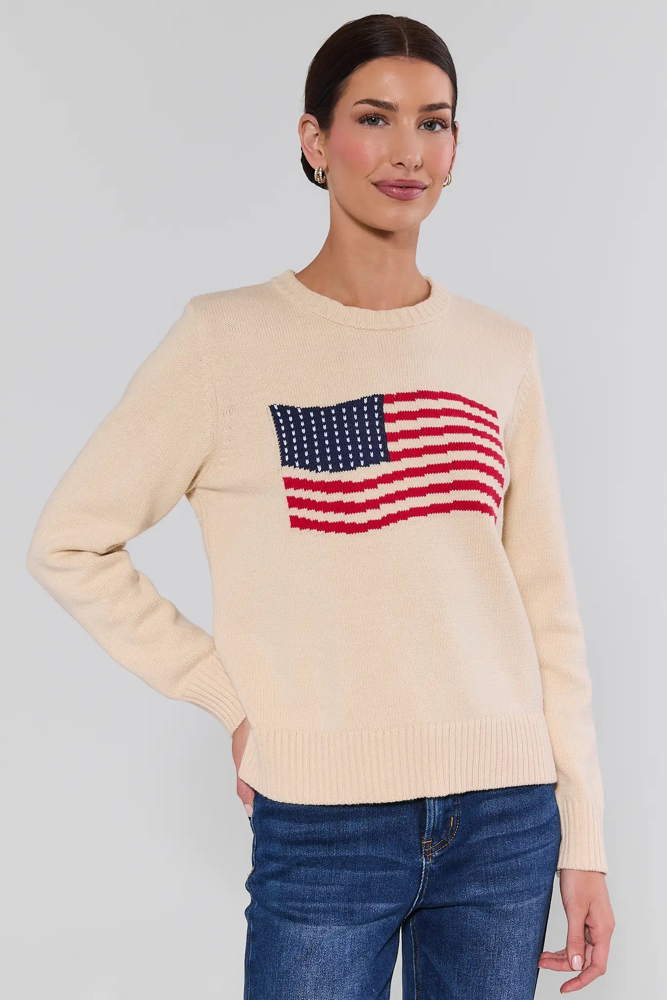 Cream American flag knit sweater on model, front view, relaxed fit styled with dark wash jeans and sandals | Avara