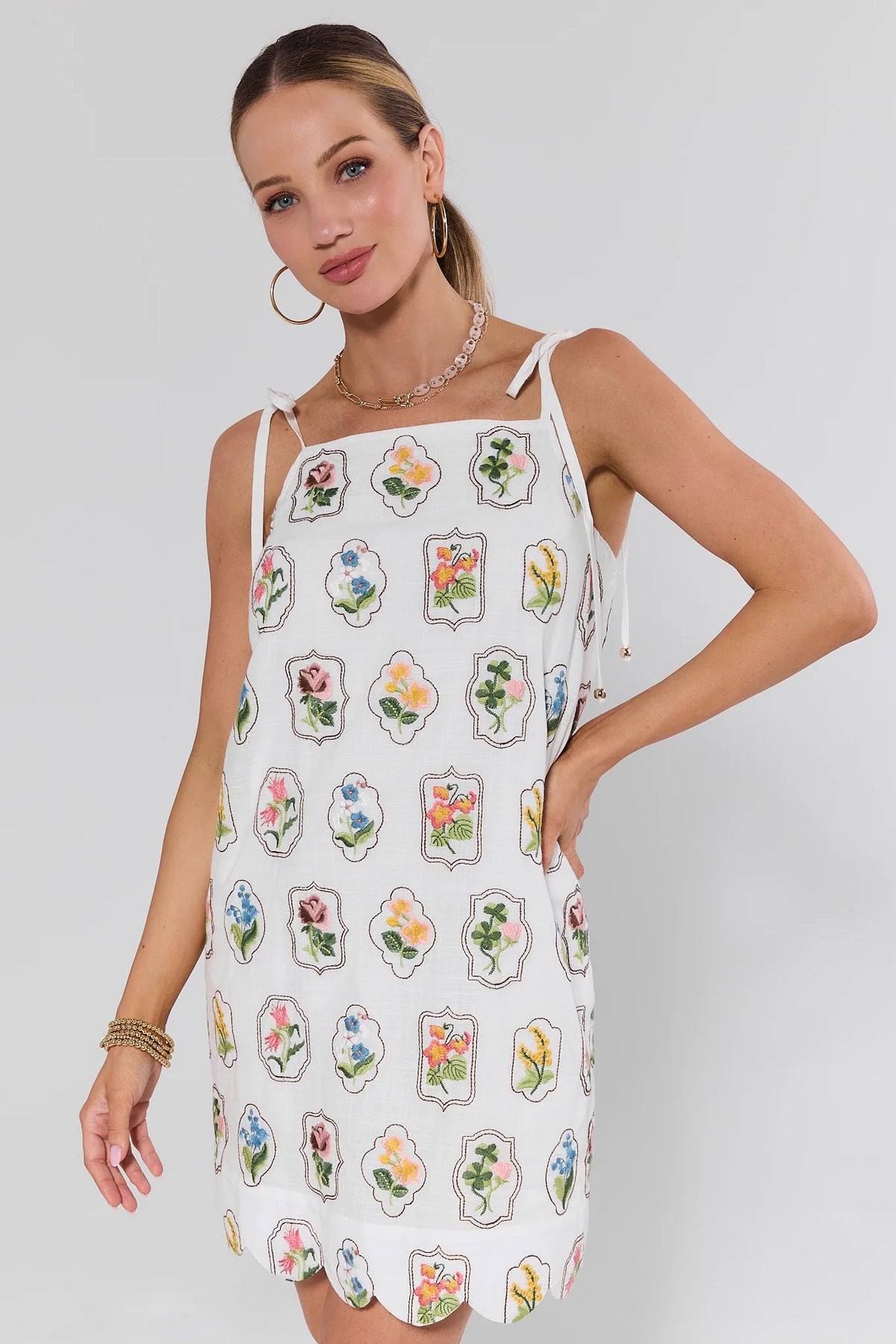 Woman wearing a white dress with floral patterns on a plain background