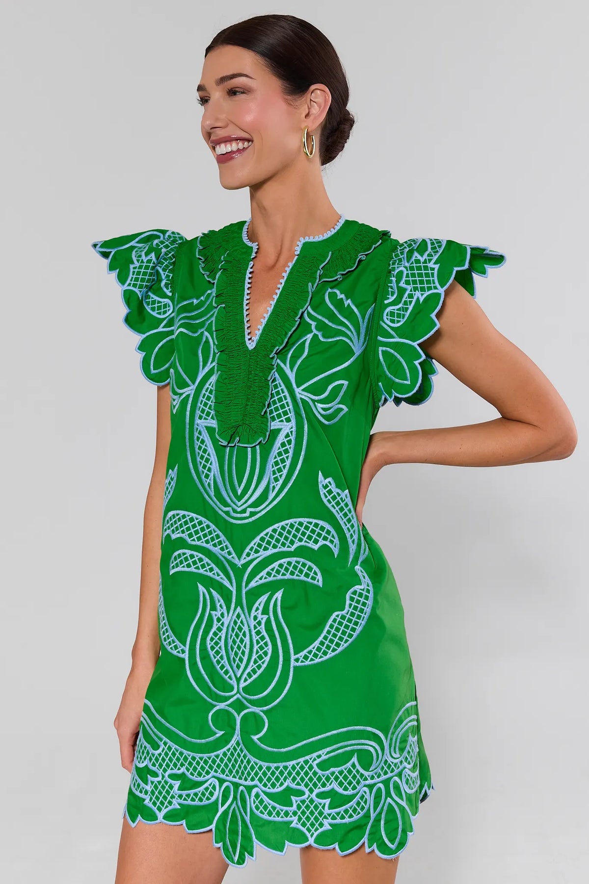 Woman wearing a green dress with white floral patterns on a plain background