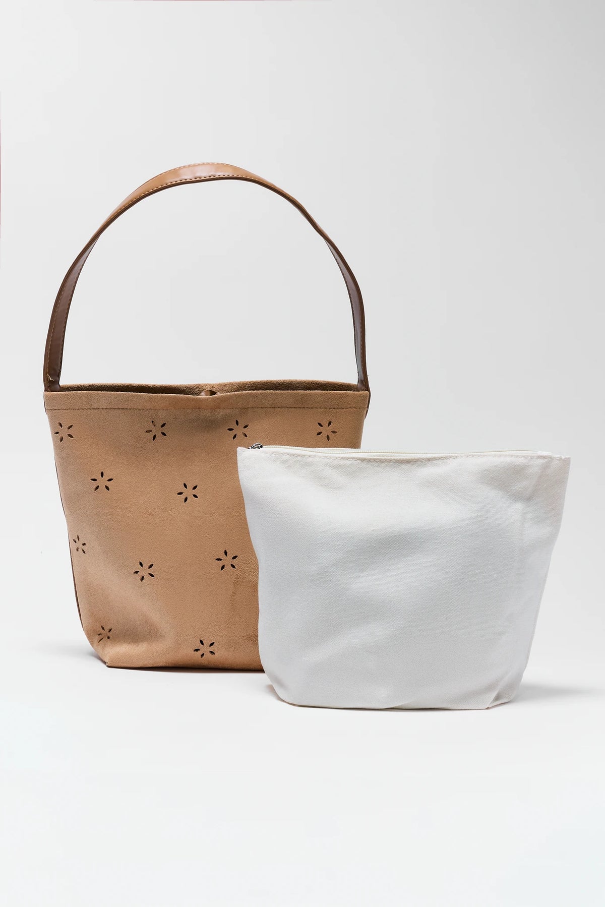 Two bags, one brown with floral cutouts and one white, on a light gray background.
