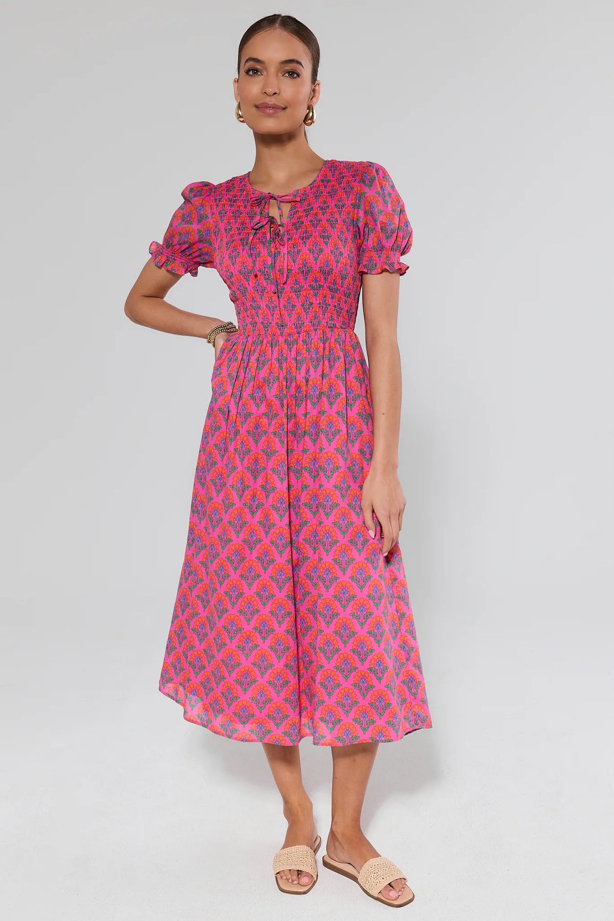 Woman wearing a pink and purple patterned dress on a white background