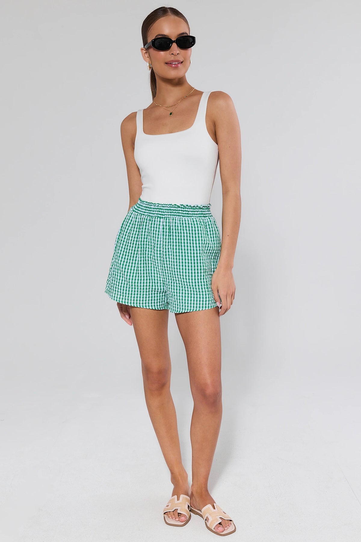 Woman wearing green gingham shorts with white tank and sandals, full-length front view, womens gingham shorts | Avara