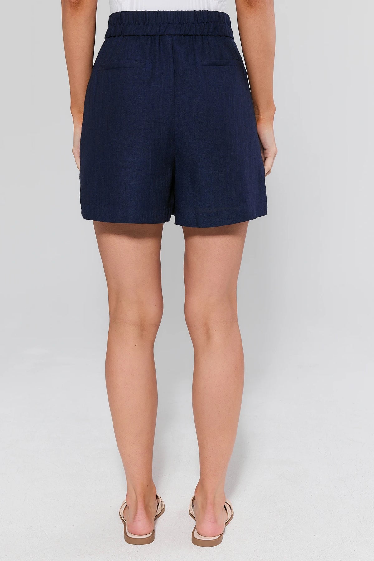 Navy blue shorts worn by a person on a white background