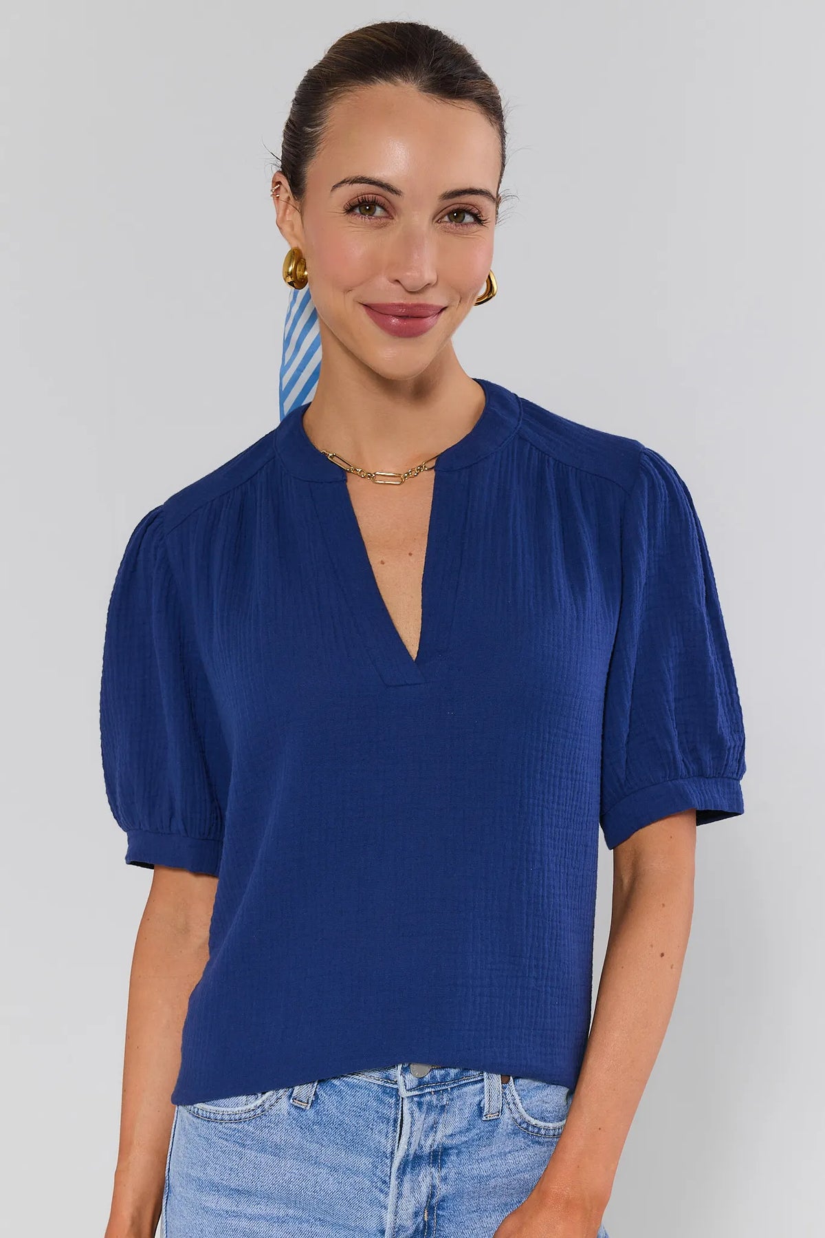 Navy gauze top with puff sleeves and split V-neckline, front view on model with light wash jeans | Avara