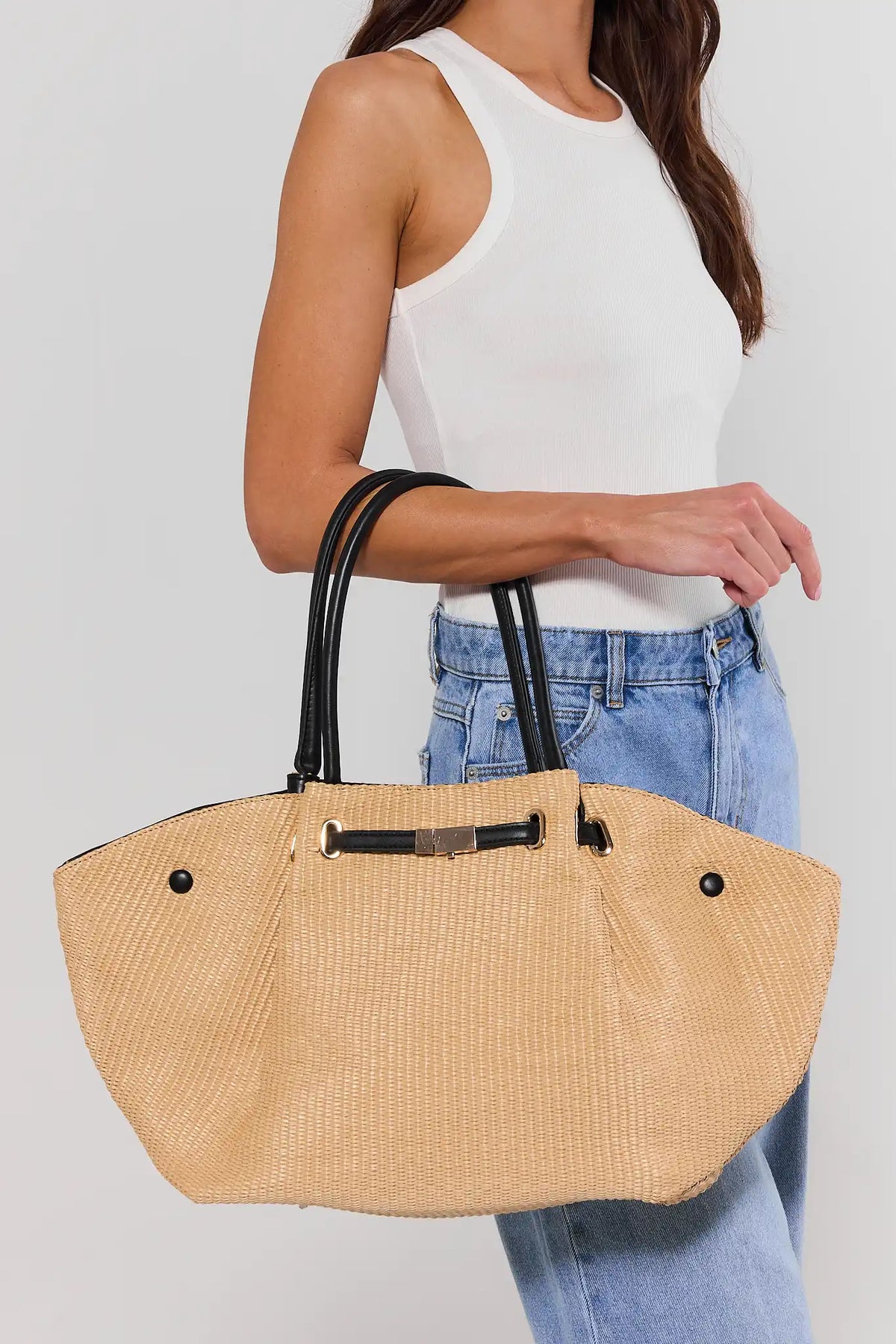 Tan straw tote bag on model wearing white tank and blue jeans - Styled Look | Avara