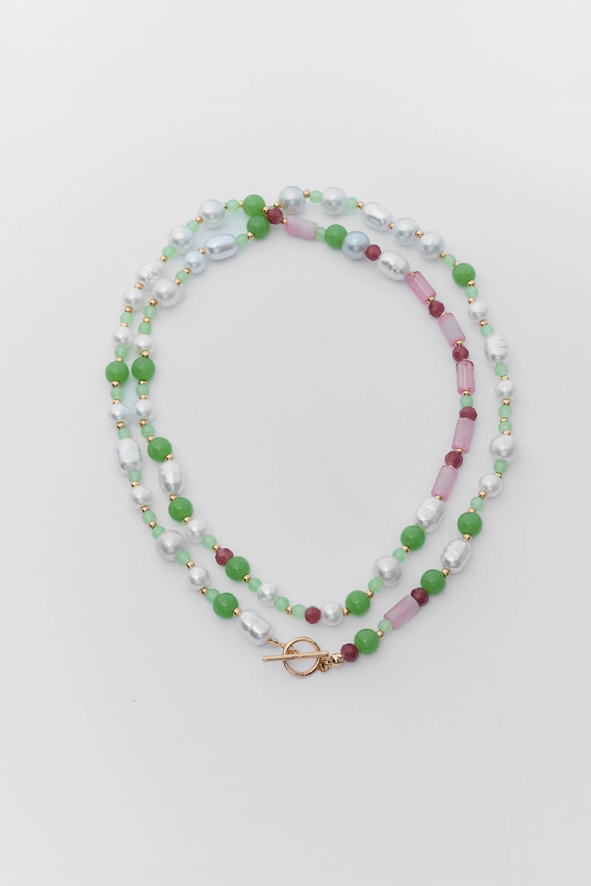 Beaded necklace with green, pink, and white beads on a light gray background