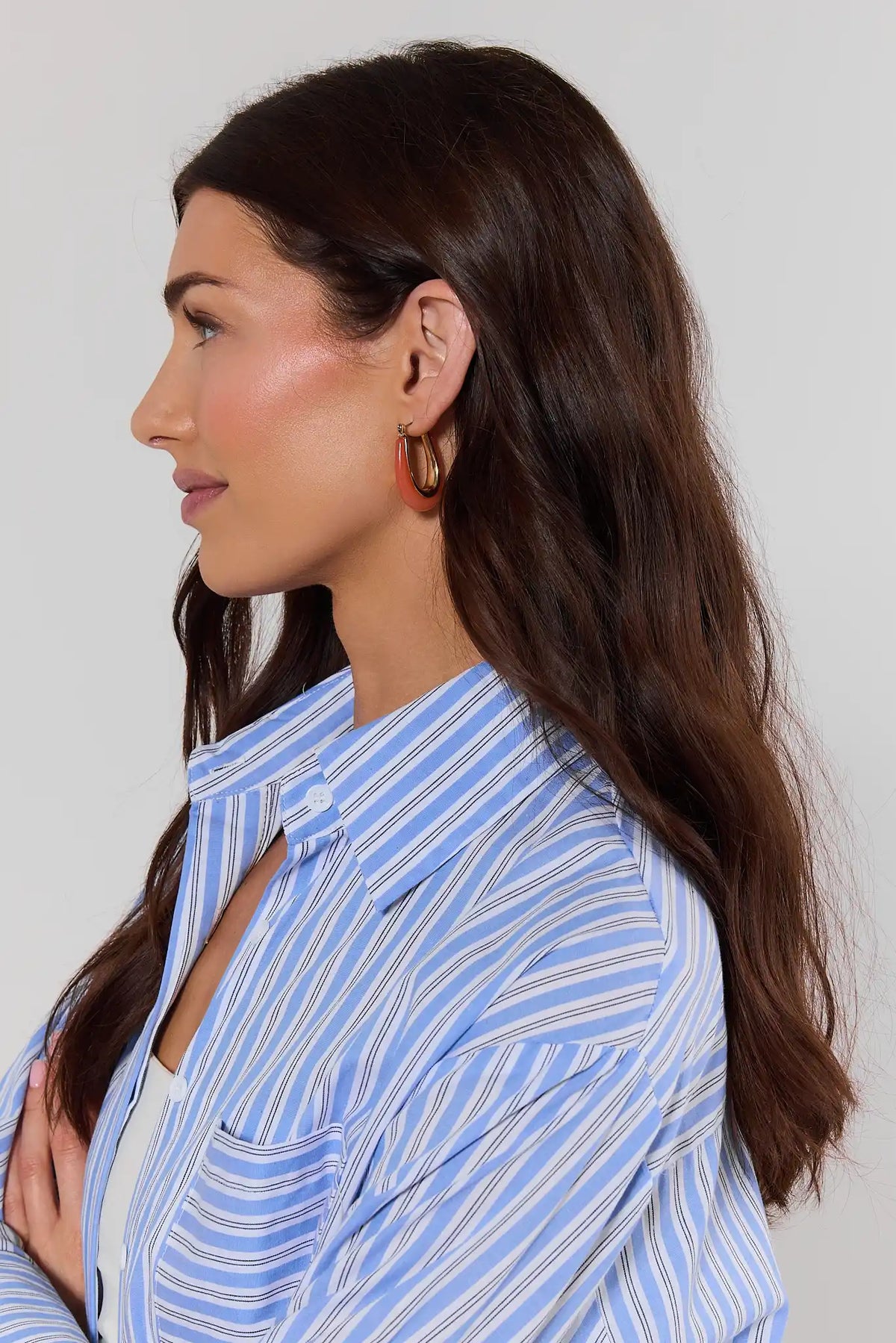 Coral acrylic hoop earrings worn on model in blue striped shirt - Side Profile | Avara