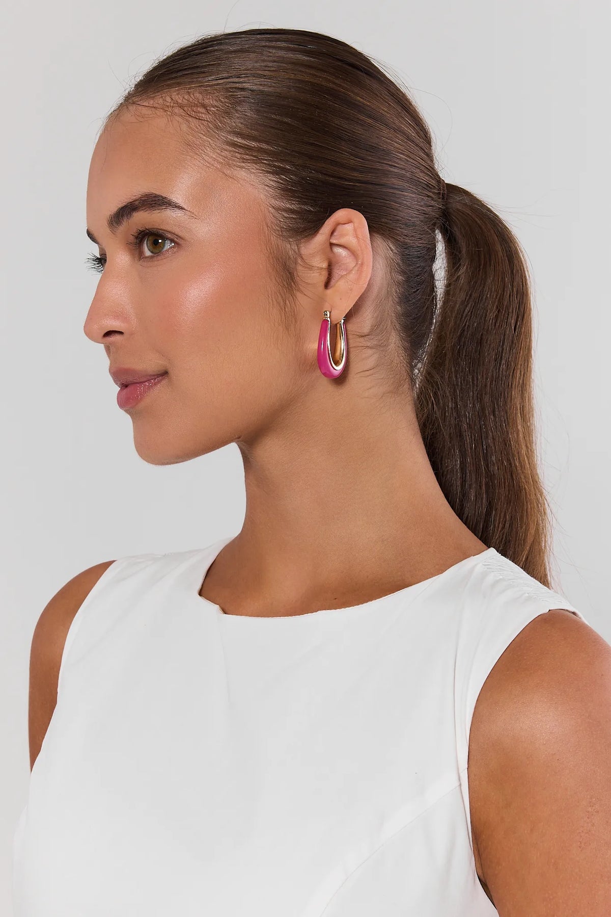 Woman with ponytail wearing pink acrylic hoop earrings with white top - Side Profile | Avara