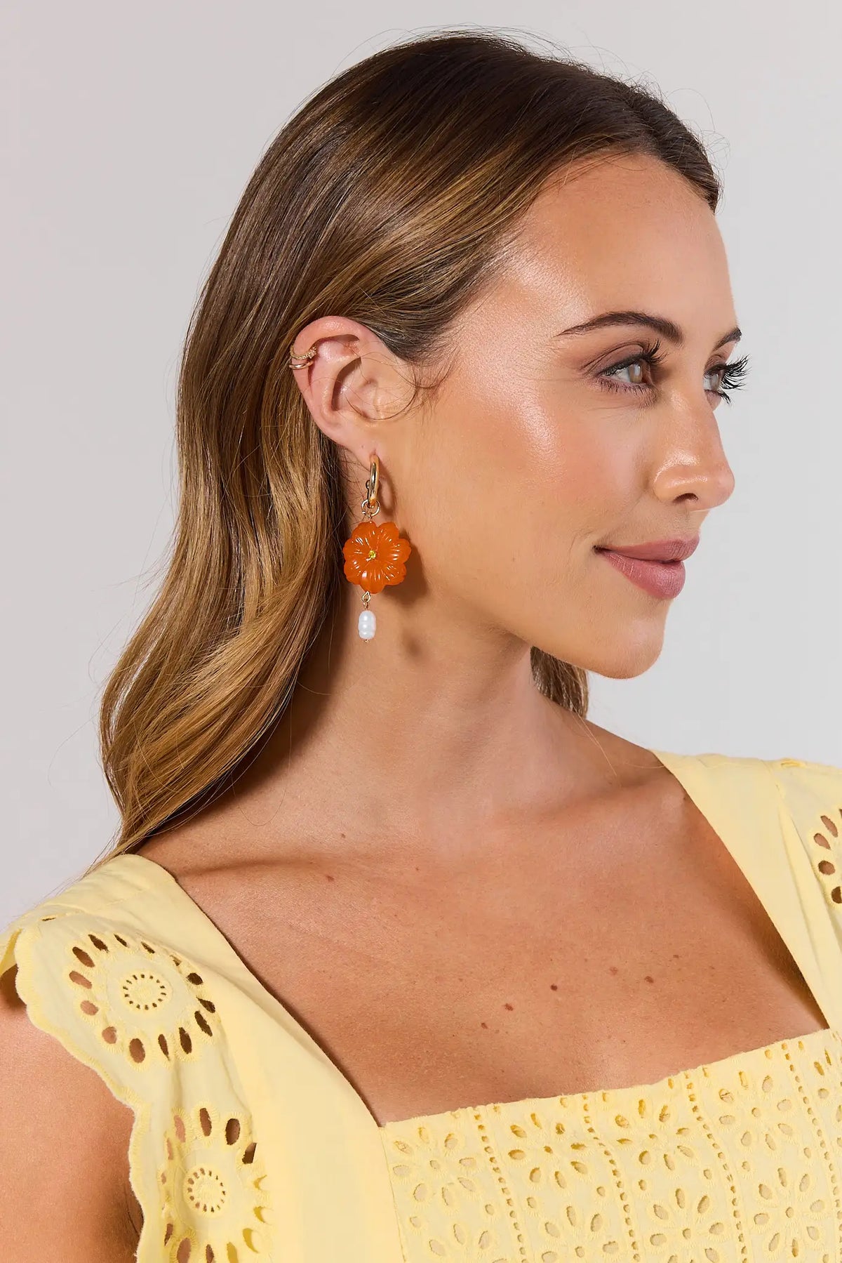 Woman wearing orange earrings with a plain background