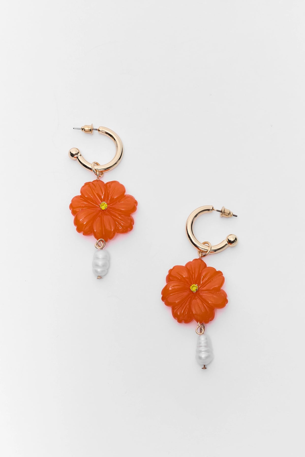 Pair of floral earrings with orange flowers and pearl-like beads on a light gray background