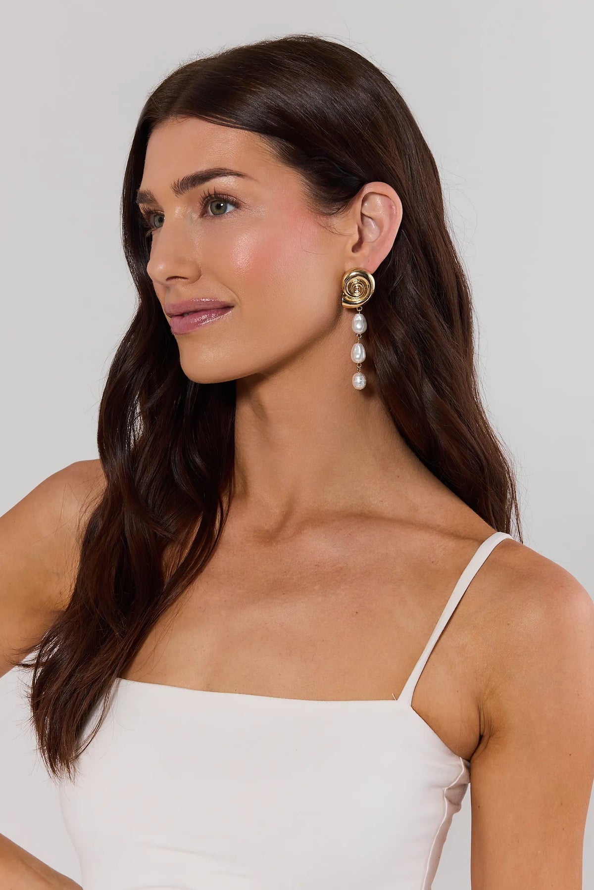 Woman wearing gold shell pearl drop earrings with spiral detail - On Model Side View | Avara