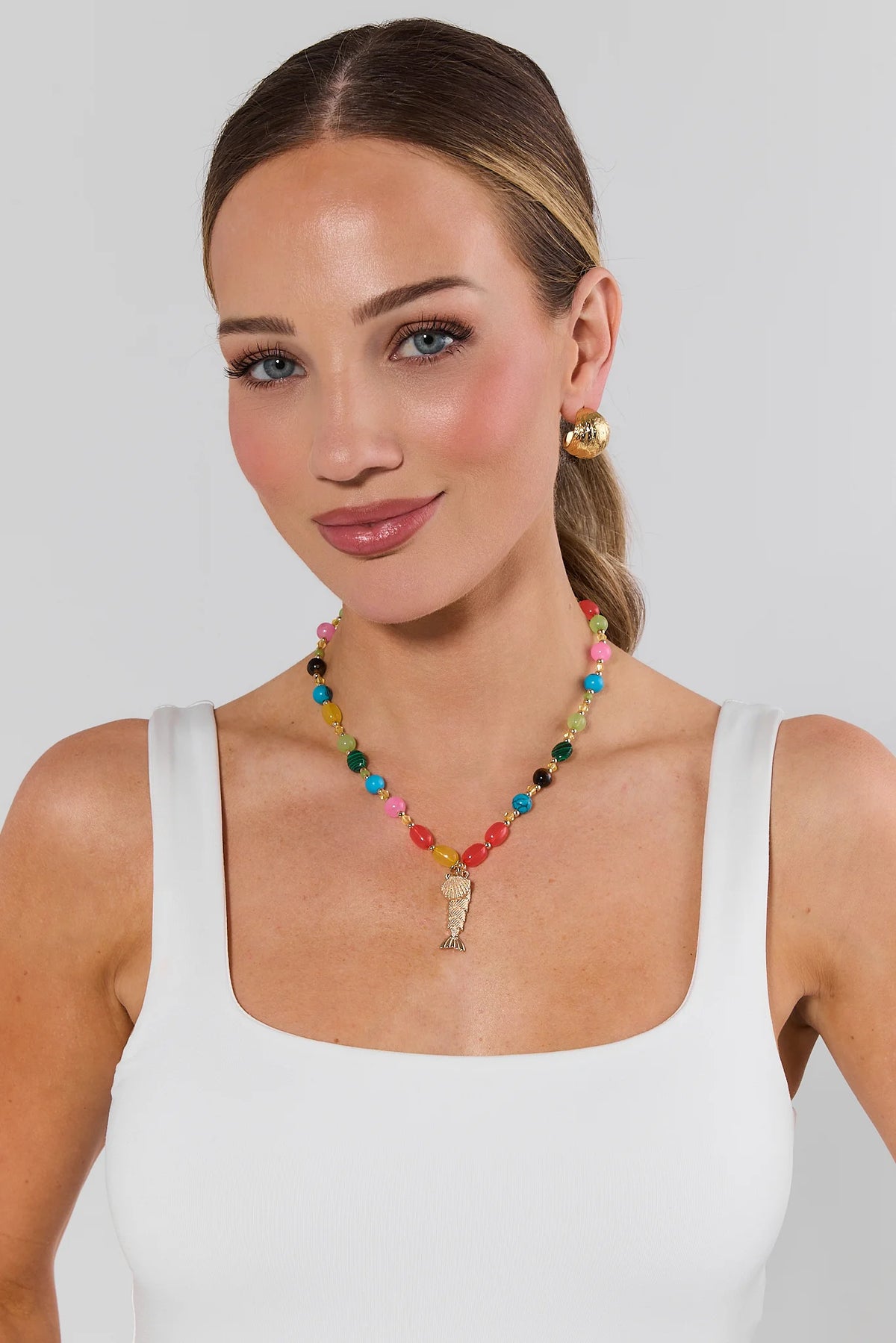 Woman wearing a colorful beaded necklace and earrings on a plain background