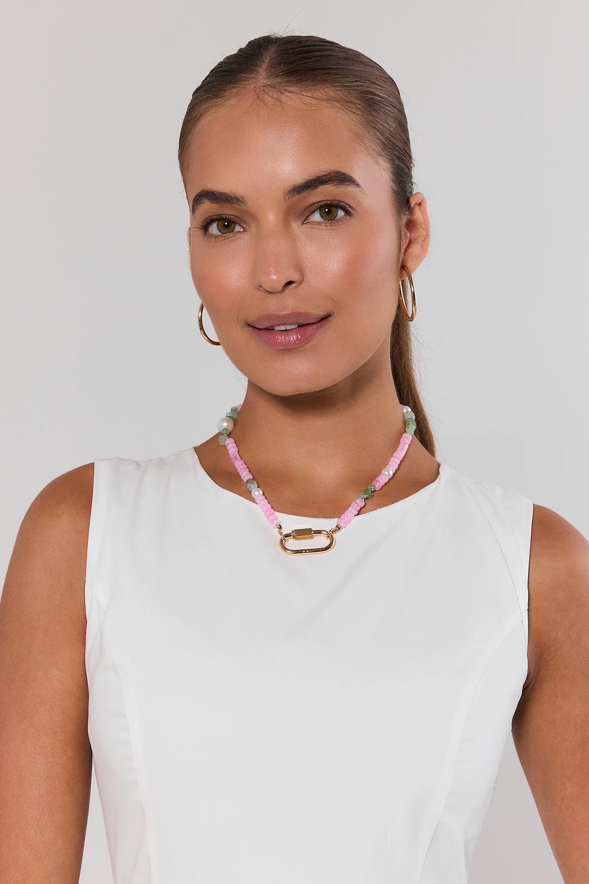 Woman wearing pink & green beaded carabiner necklace with gold clasp over white sleeveless top - On Model | Avara