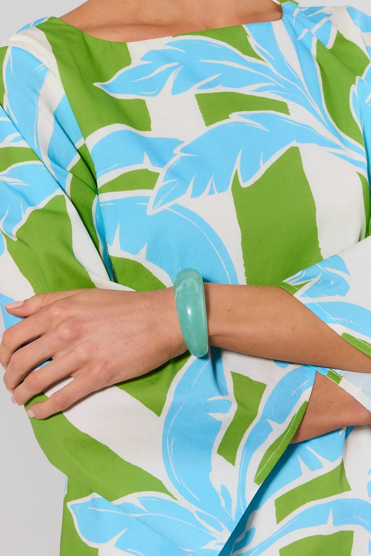 Person wearing a green and blue floral dress with a matching bracelet.