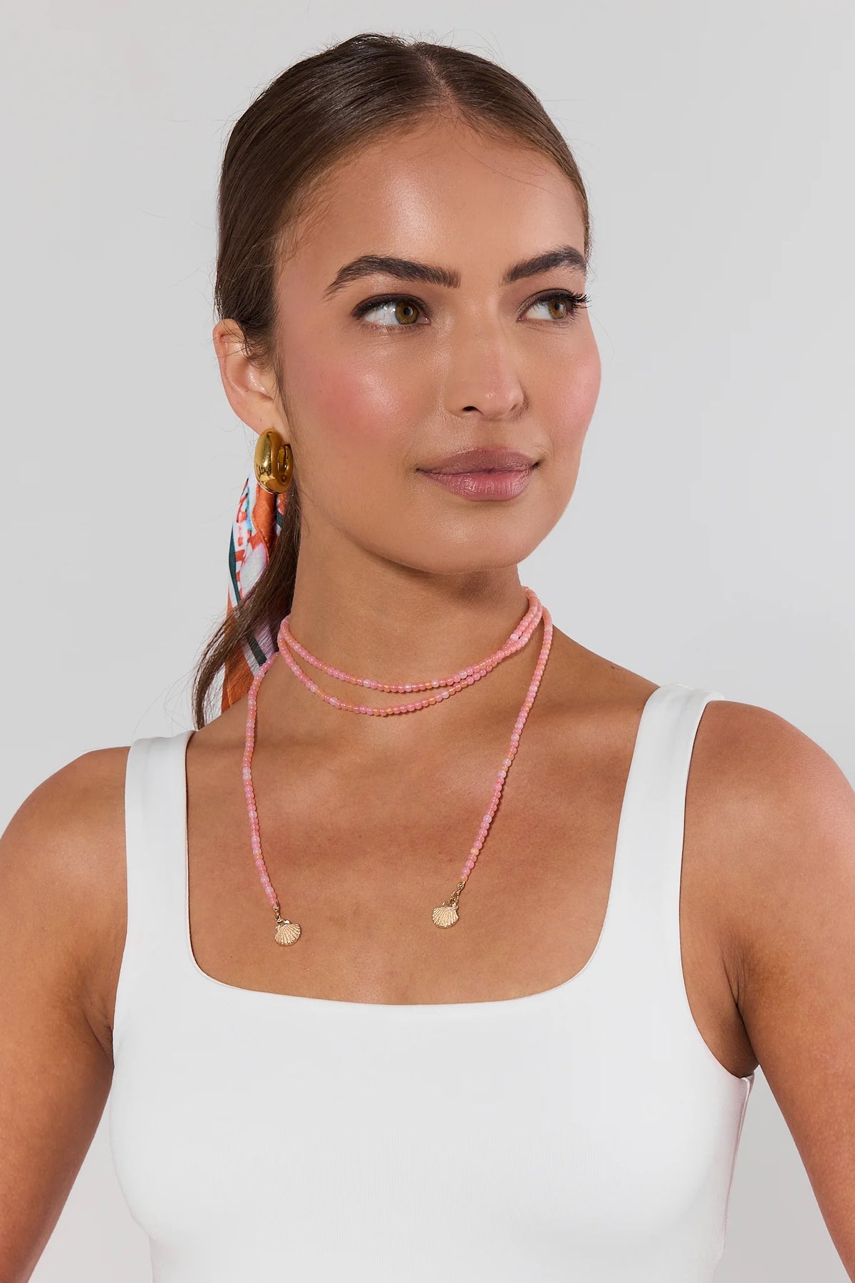 Pink beaded wrap necklace worn doubled as layered choker with two gold shell charms, white tank - On Model | Avara