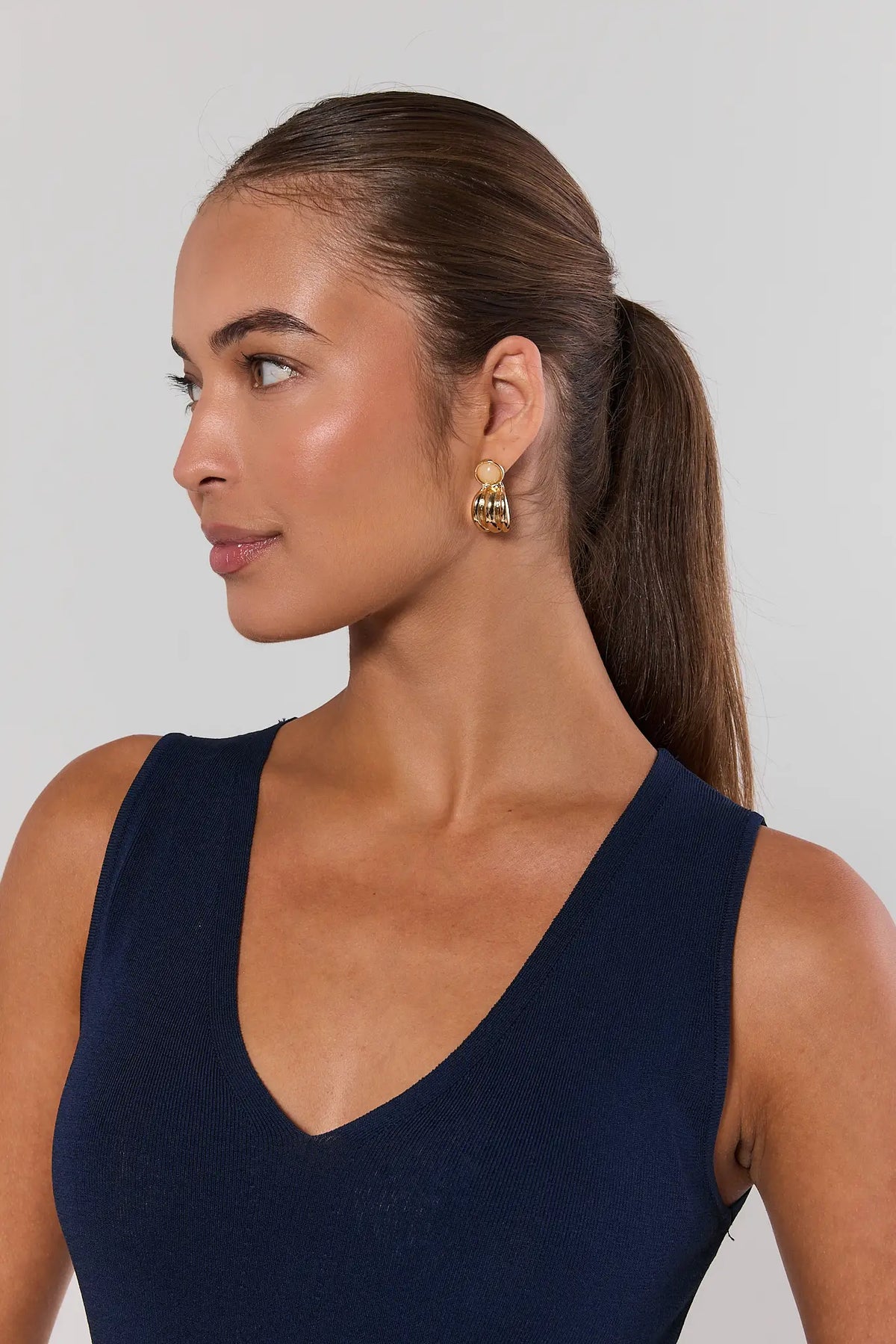 Woman wearing gold fluted stud earrings with stone detail - Side Profile On Model | Avara
