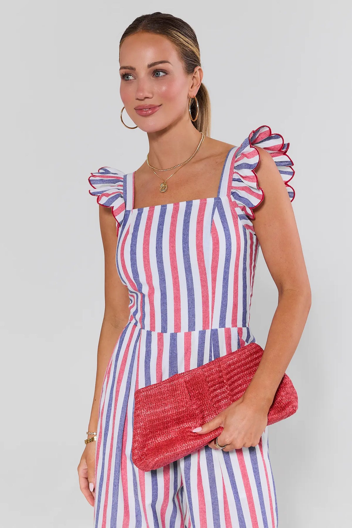 Woman in striped ruffle dress carrying pink woven raffia clutch - Close-Up Detail | Avara