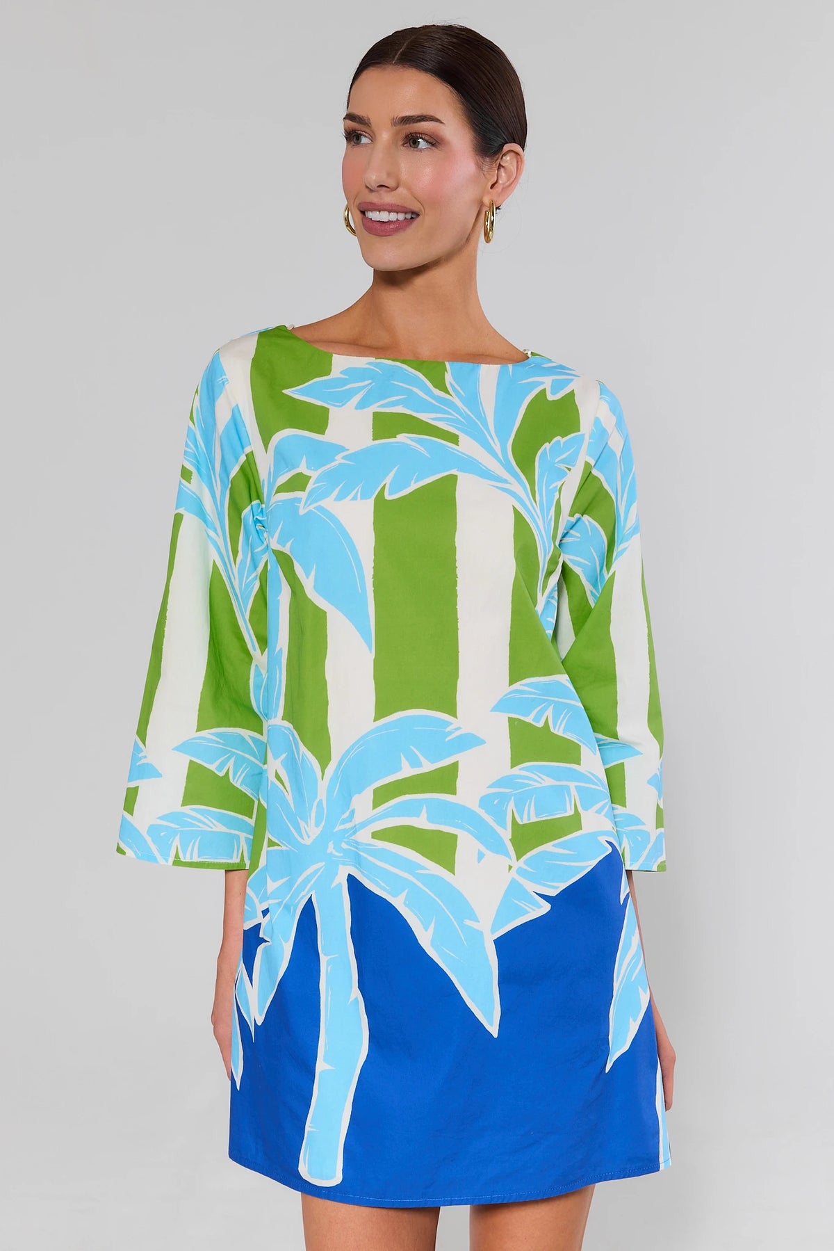 Woman wearing a colorful dress with palm tree design on a plain background