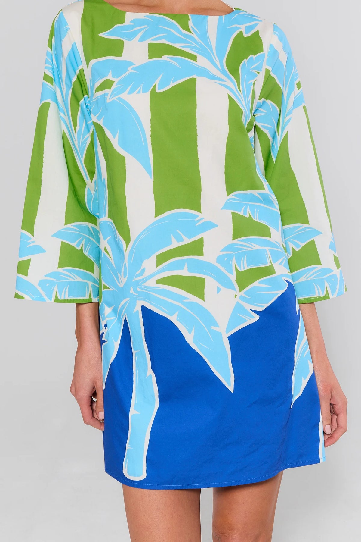 close up Woman wearing a dress with green and blue palm tree pattern on a white background