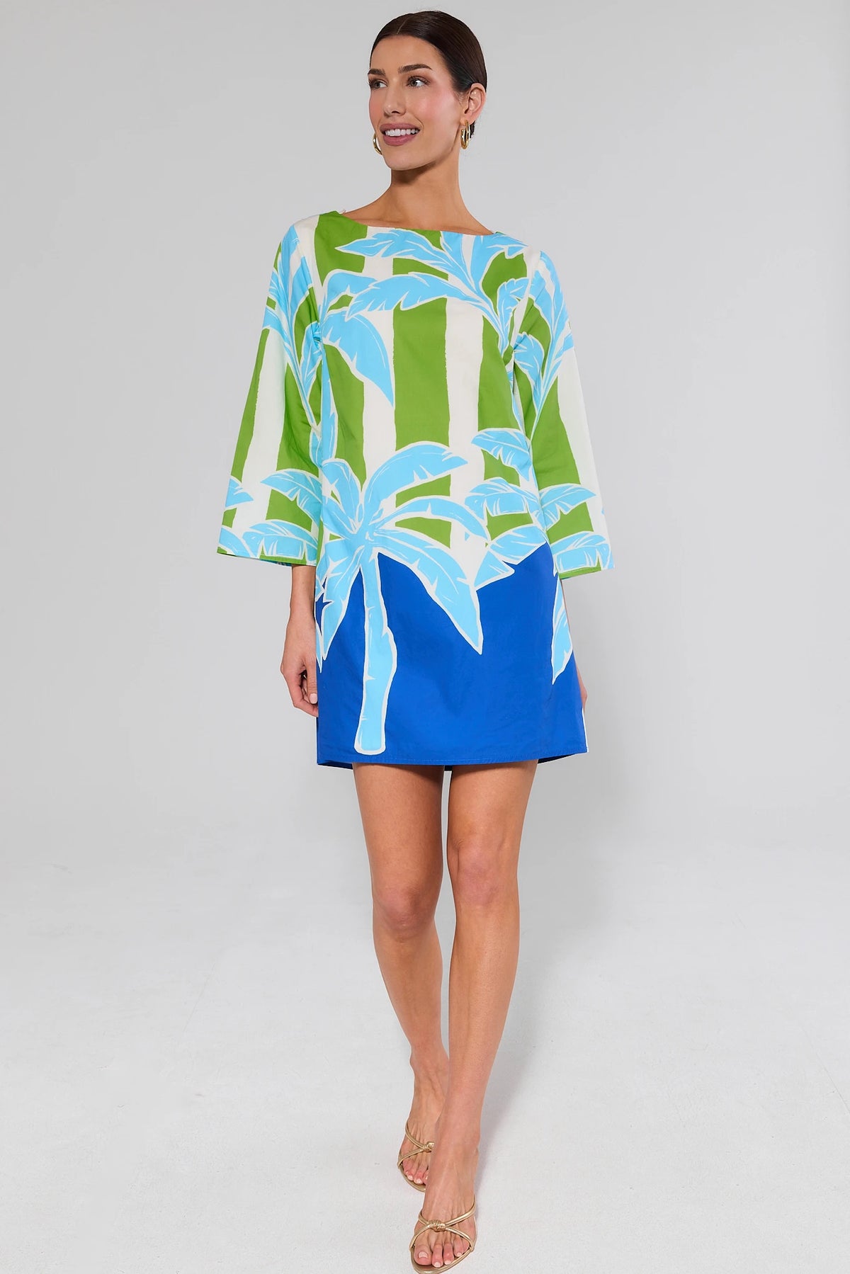 Woman wearing a blue and green dress with a floral pattern on a plain background