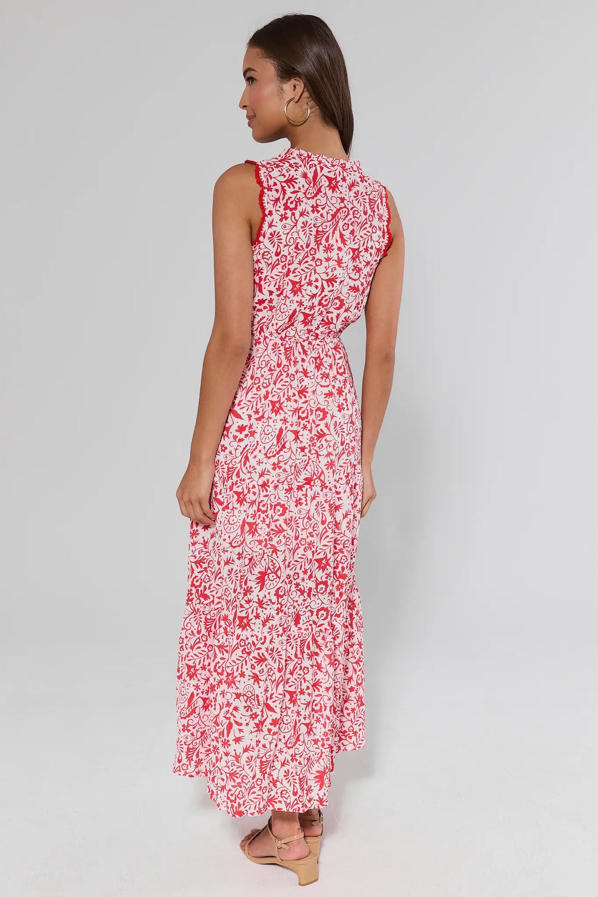 Woman standing wearing a red floral dress on a gray background