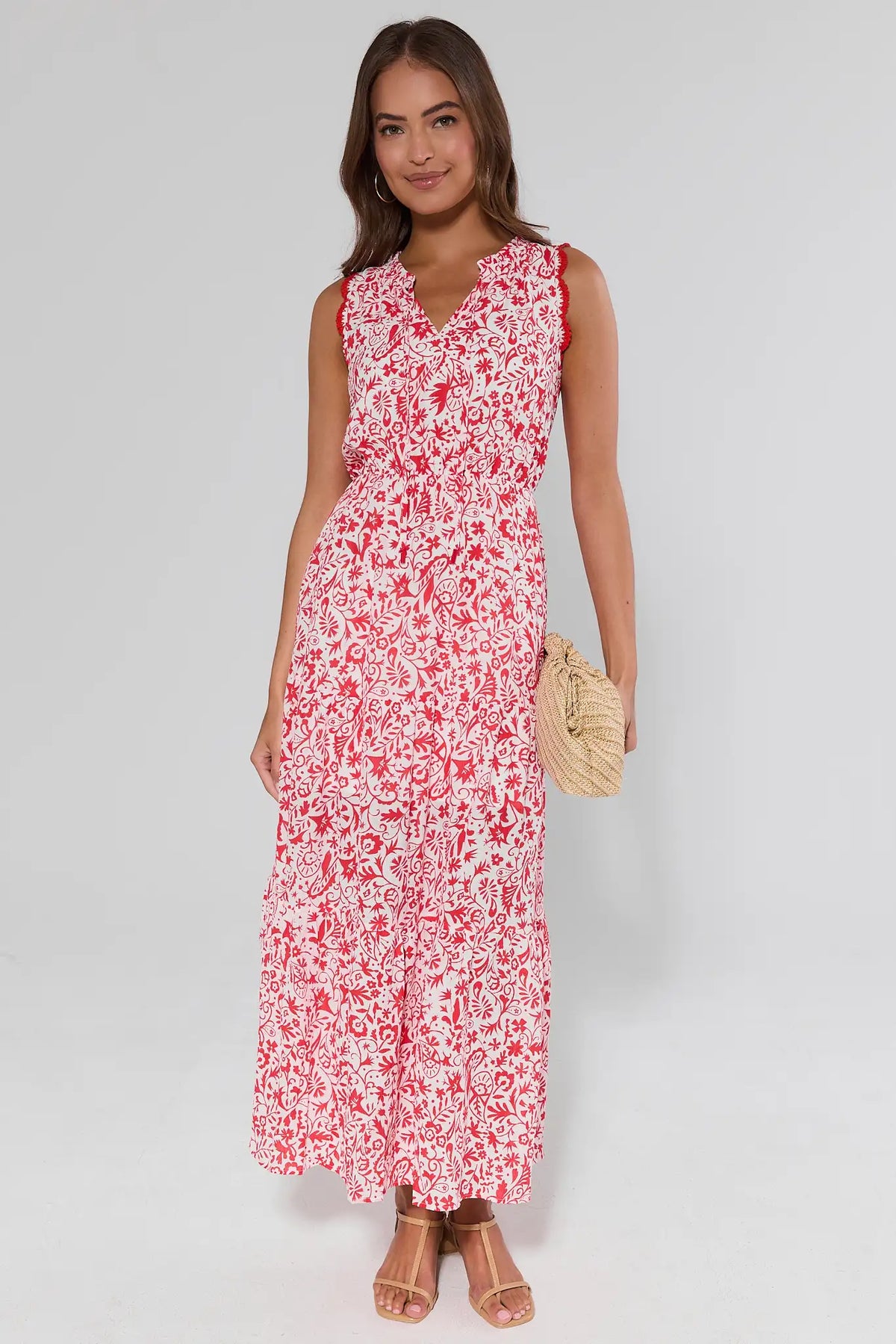 Woman wearing a red floral dress and clutch on a gray background
