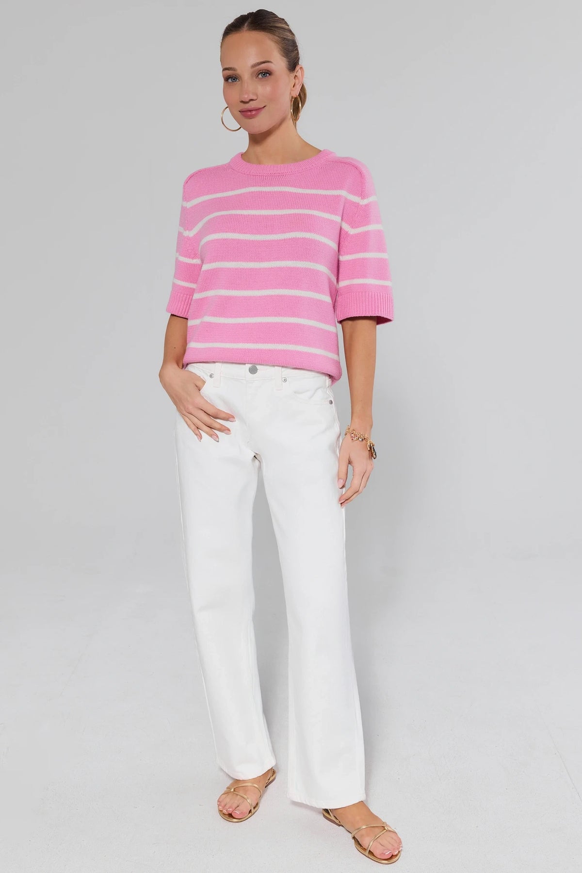 Women's white barrel leg jeans styled with pink striped sweater and gold sandals, full-length on model | Avara
