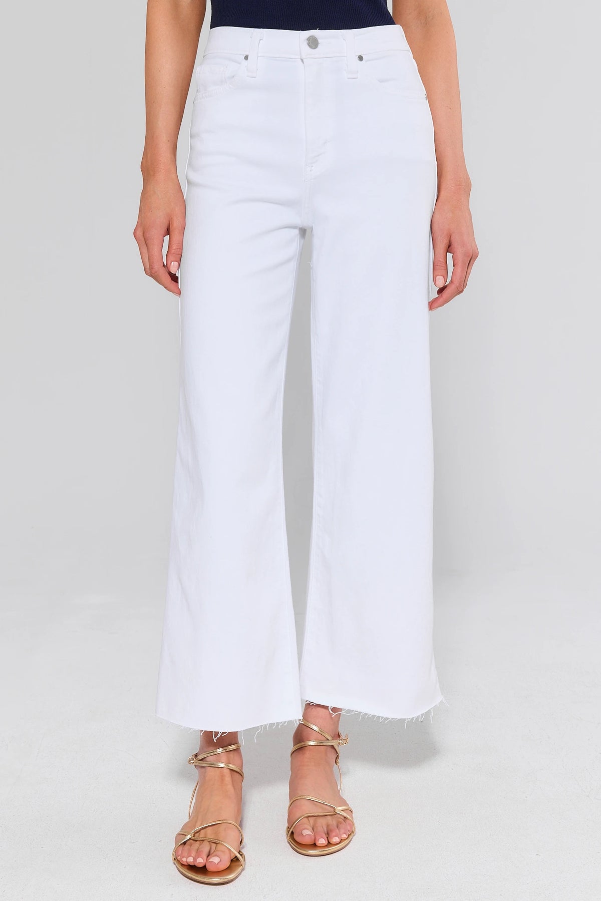 White wide leg jeans front view, high-rise with raw hem, styled with gold sandals | Avara