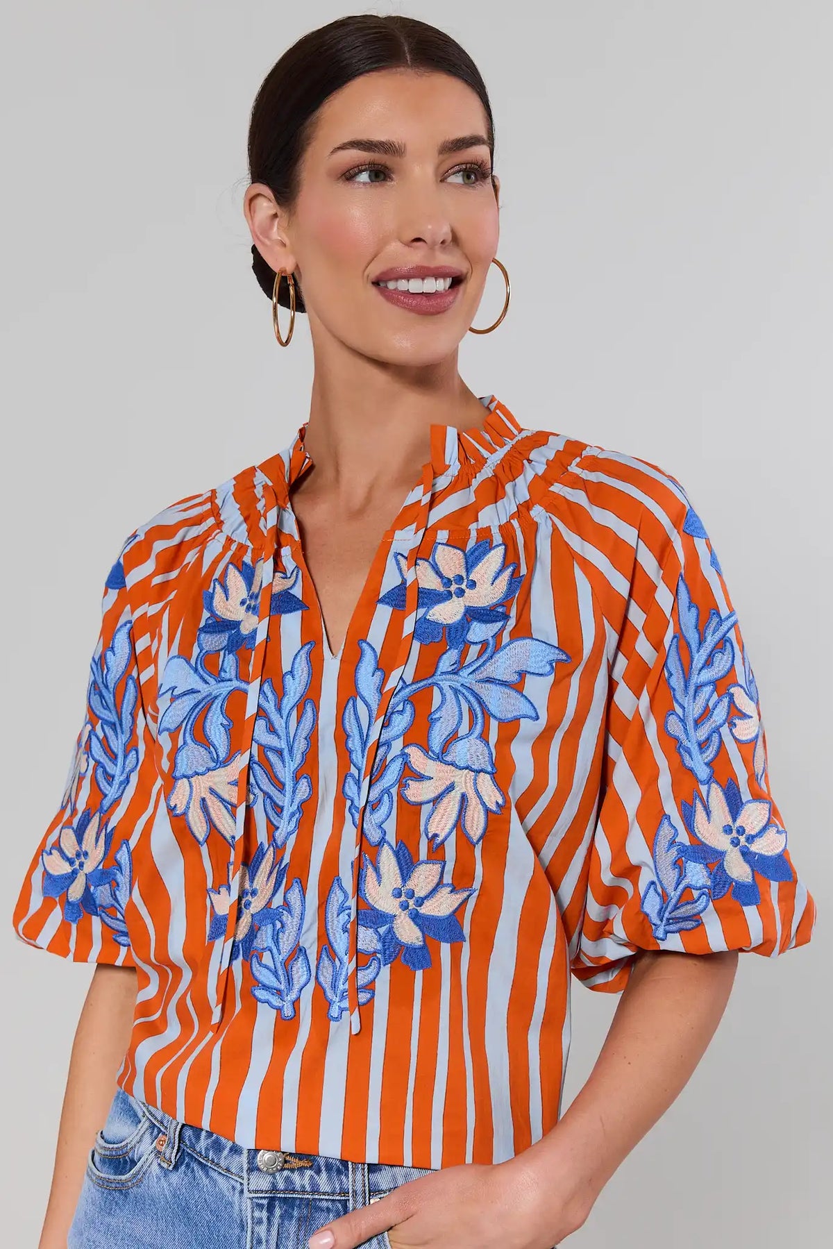 Close-up of orange striped embroidered top by THML showing blue floral embroidery detail and smocked neckline | Avara