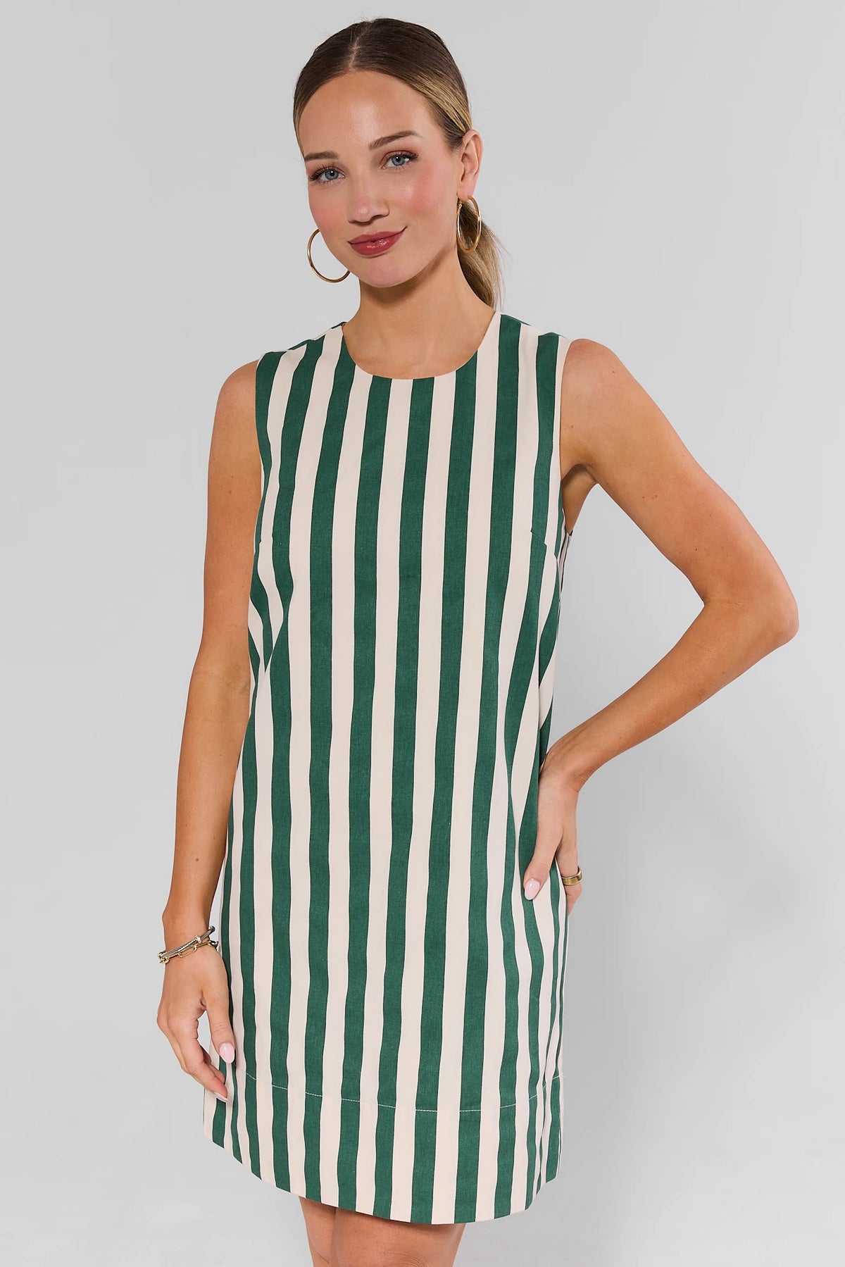 Woman wearing green and white striped sleeveless short dress, front view, relaxed silhouette | Avara