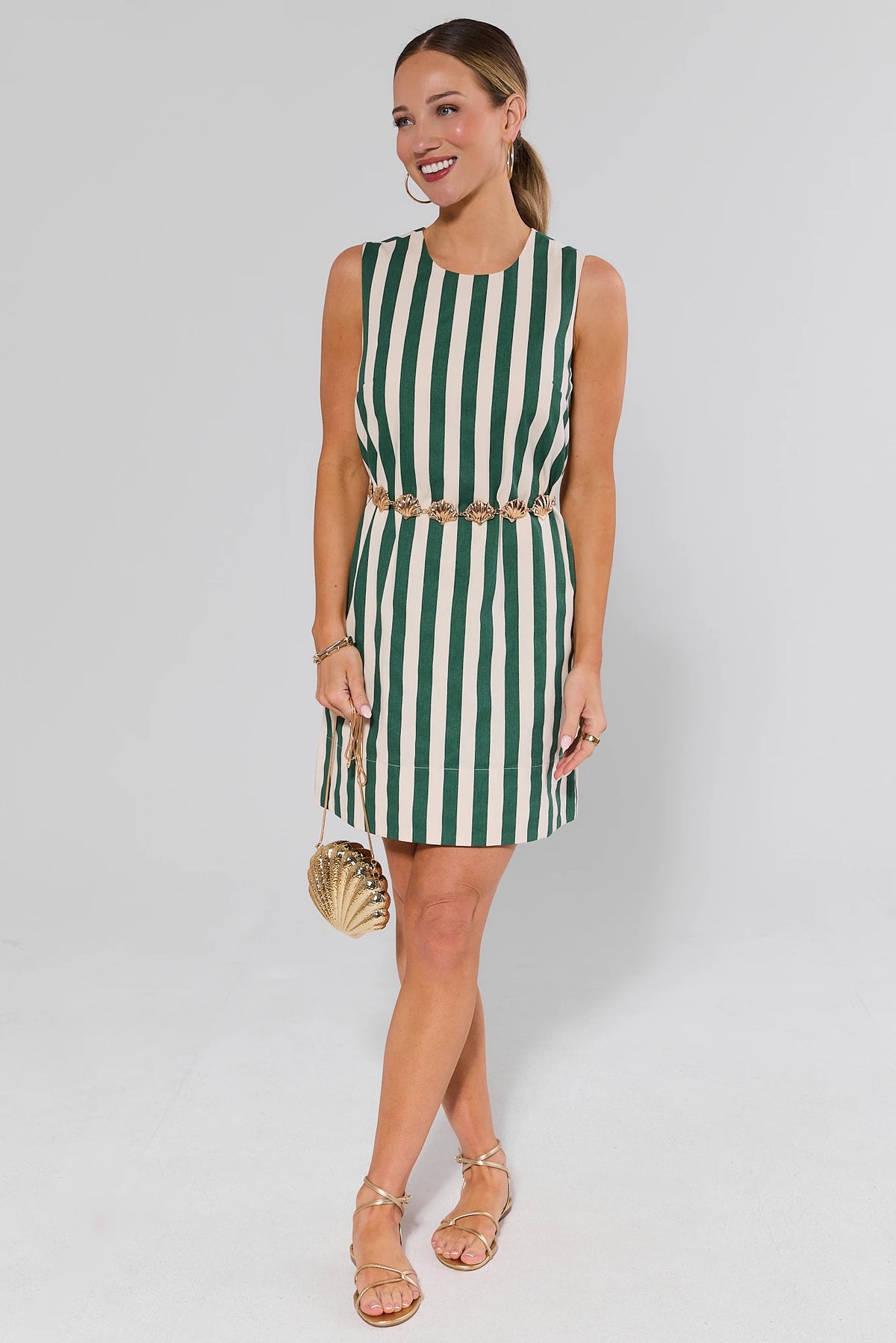 Green striped short dress styled with gold shell belt and sandals, full-length front view | Avara