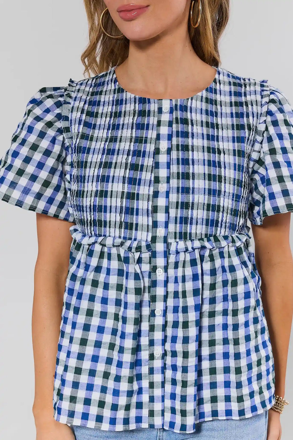 Close-up of navy blue gingham peplum top smocked bodice and button front detail | Avara