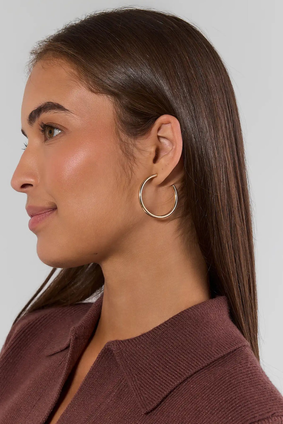 Emily Gold Small Hoop Earrings worn by model in side profile, styled with burgundy top | Avara