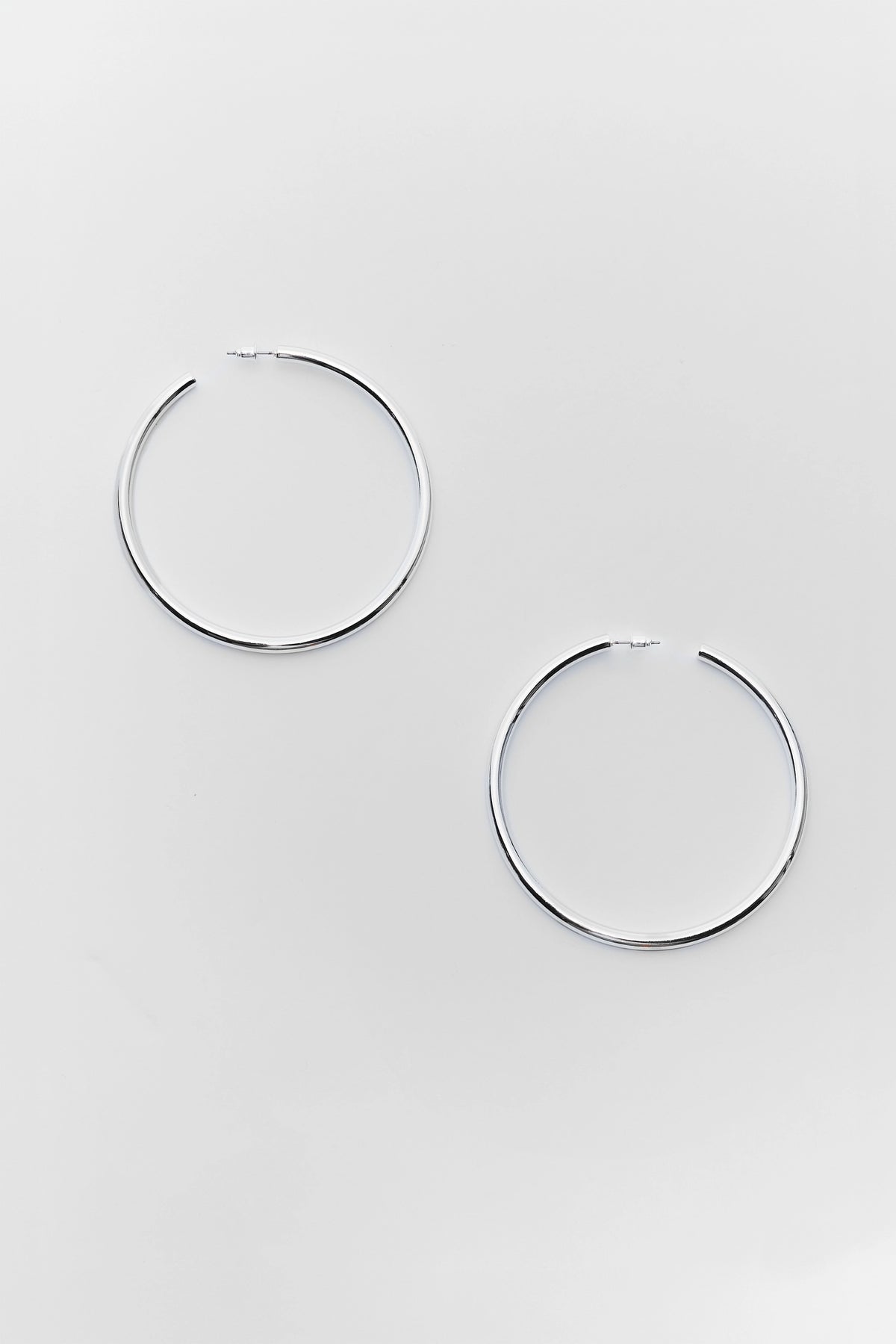 Pair of large polished silver hoop earrings - Flat Lay | Avara