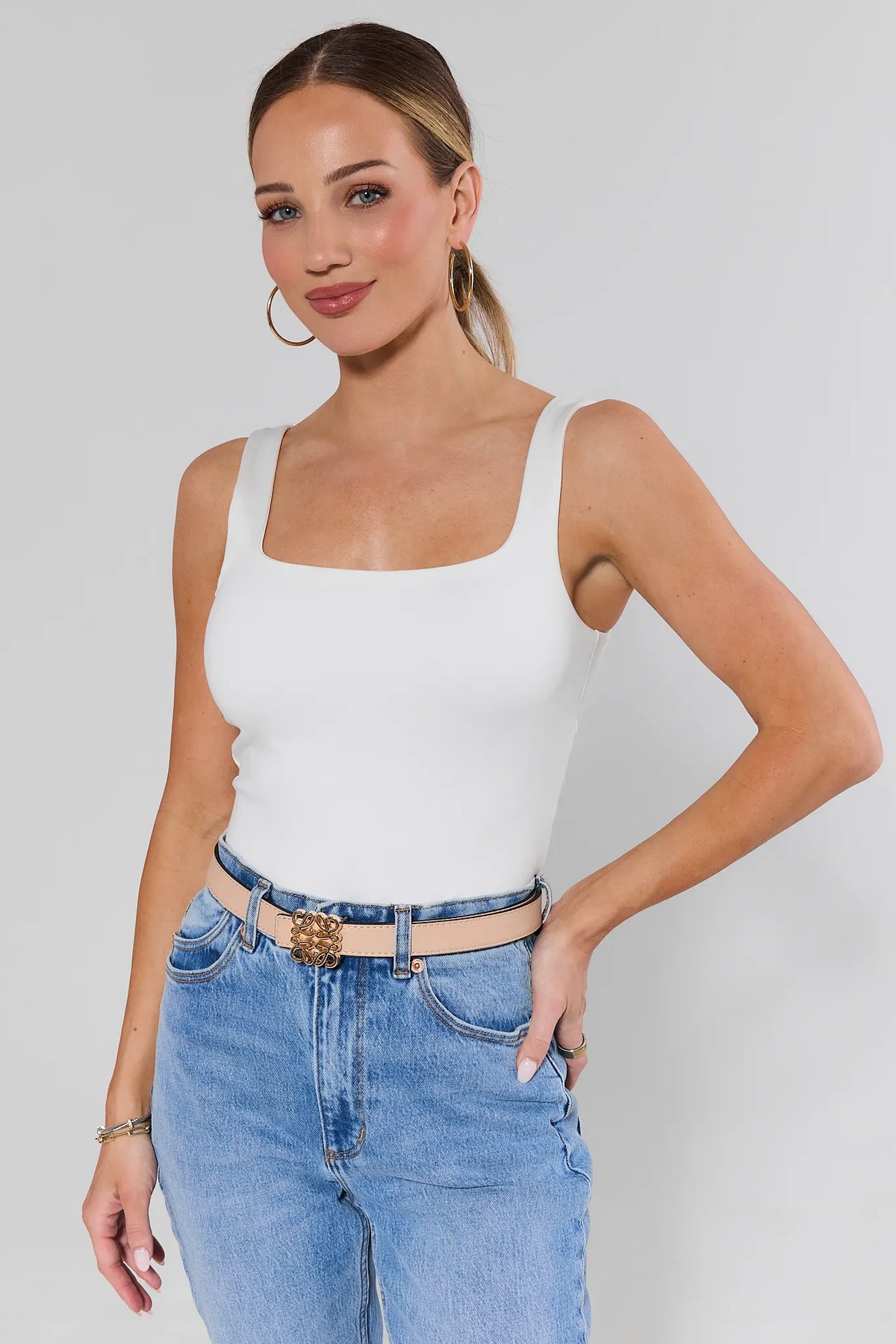 Woman wearing Rowan Tan Faux Leather Belt with white tank and blue jeans, gold buckle - On Model | Avara