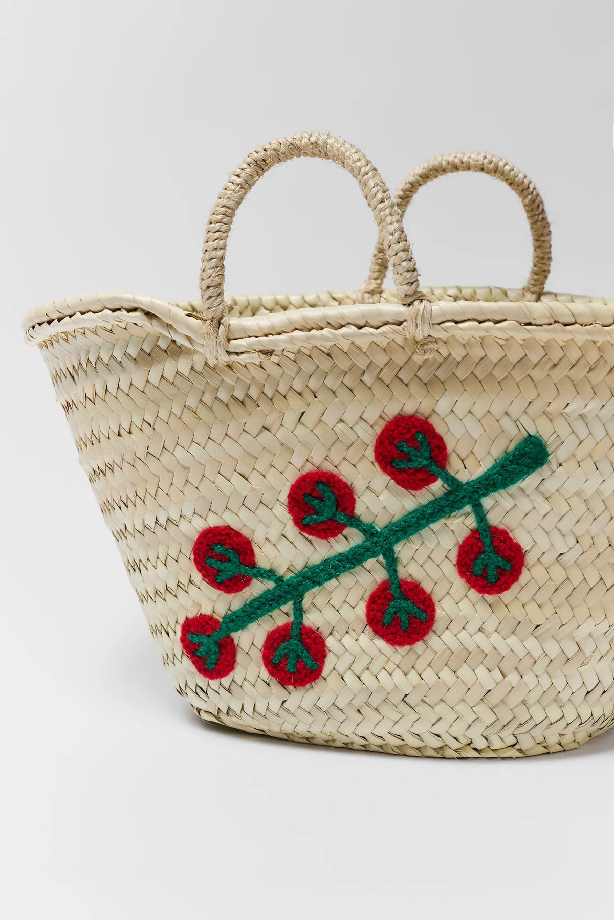 Tan woven raffia tote close-up showing red tomato crochet detail and double handles | Avara